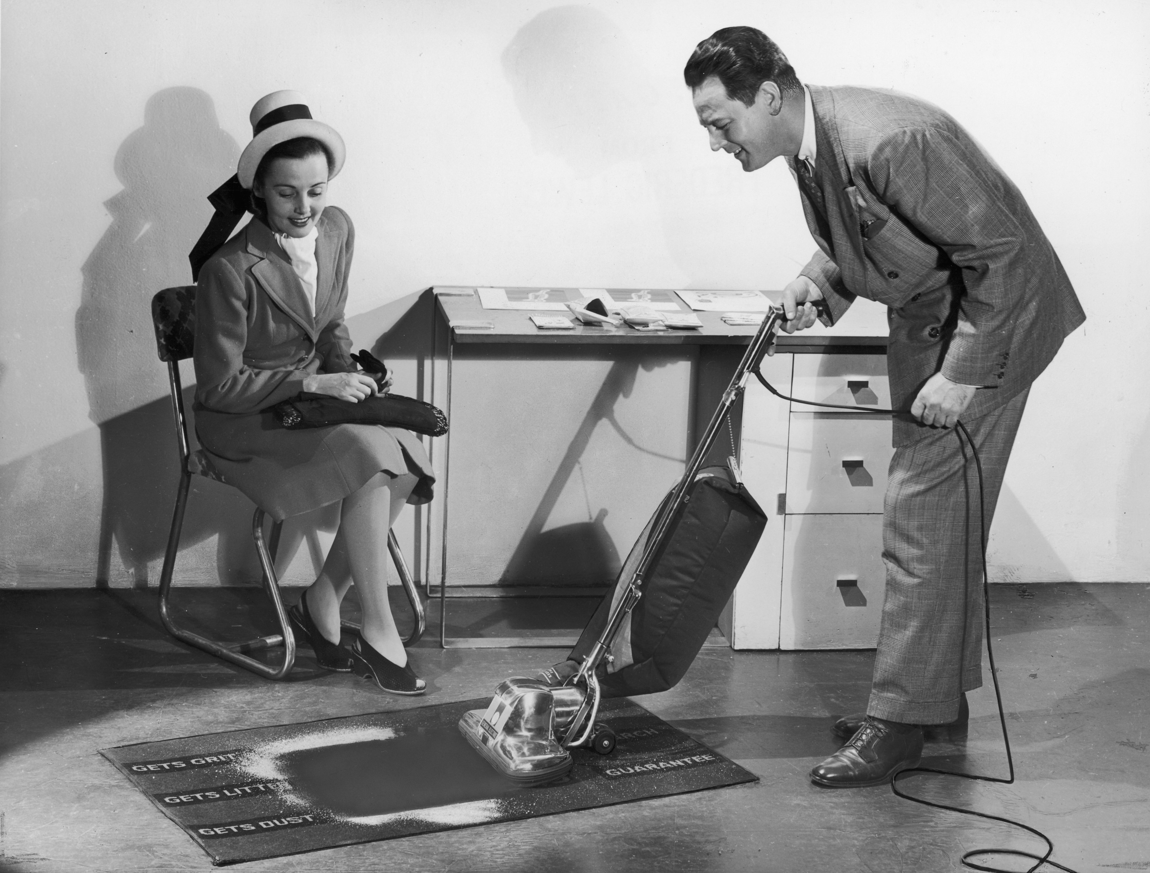 A salesman demonstrates the effectiveness of a General Electric vacuum cleaner to a prospective customer. | Photo: Getty Images