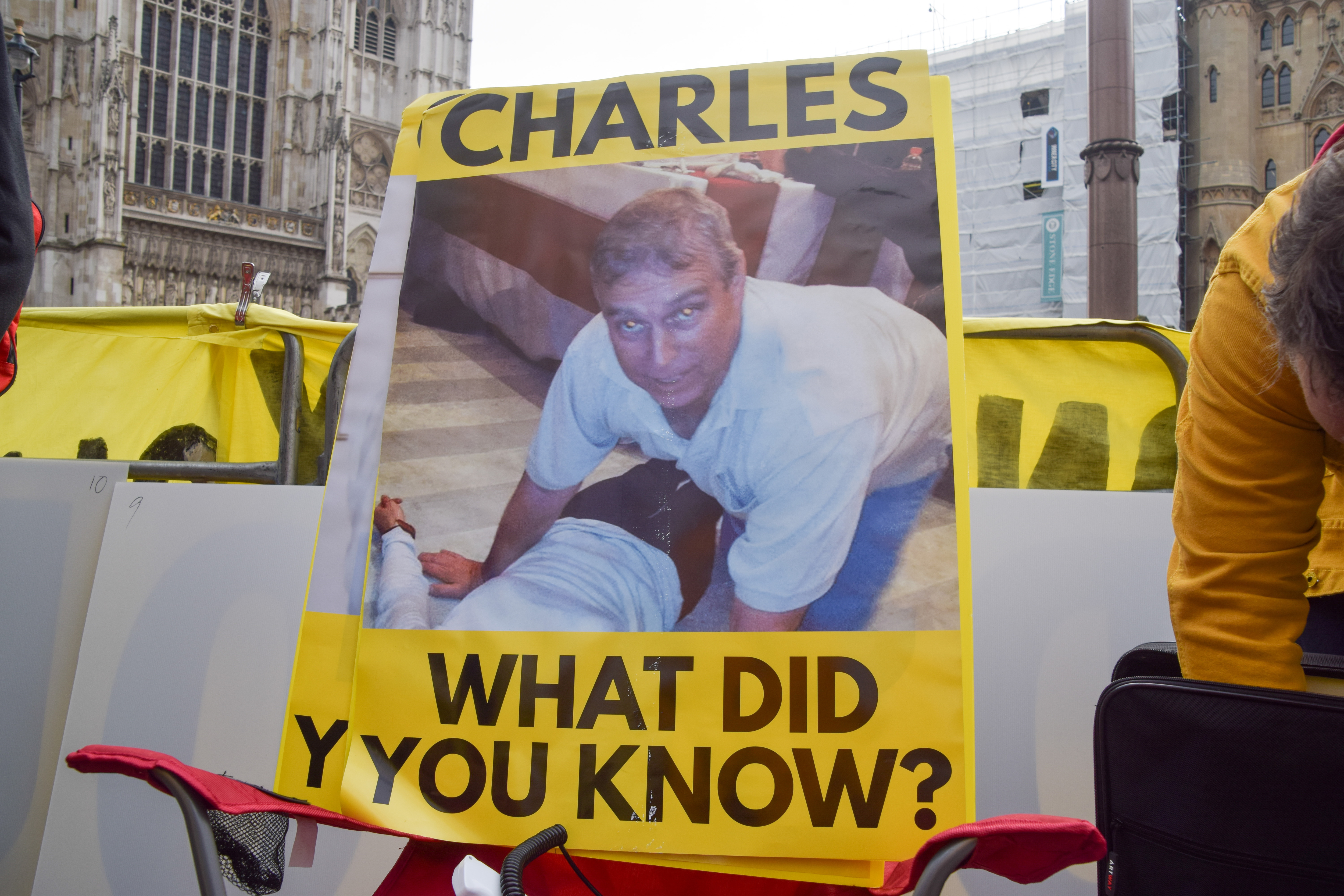 A photo of Andrew Mountbatten-Windsor kneeling over a woman lying on a floor along with the question, "Charles, what did you know" is displayed during a protest by anti-monarchy group Republic outside Westminster Abbey ahead of the arrival of King Charles III and other members of the royal family for the Commonwealth Day Service on 9 March 2026 in England. | Source: Getty Images