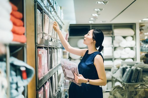 Smiling pregnant woman shopping for home necessities in shop | Photo: Getty Images