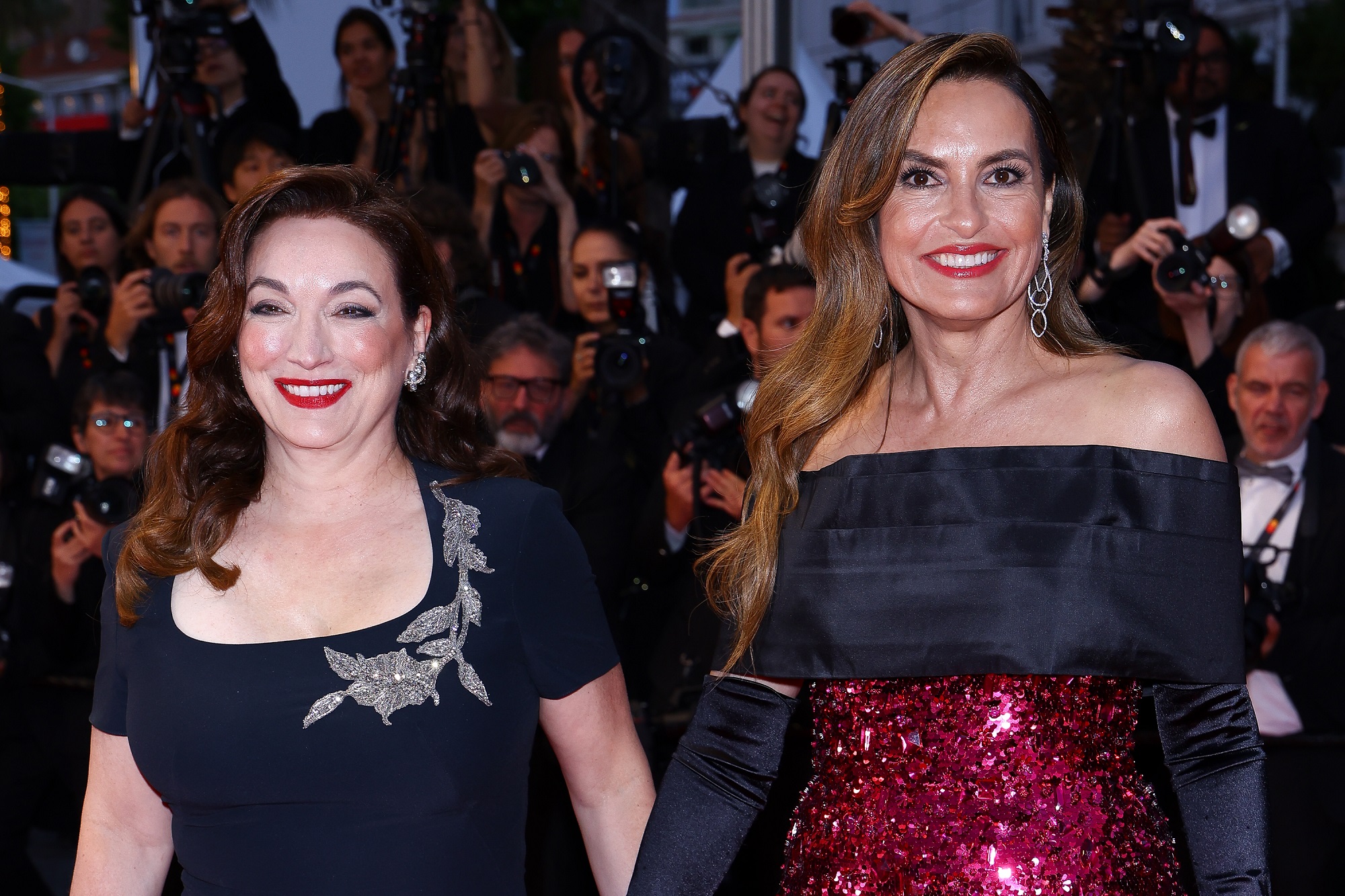 Mariska holds hands with Trish Adlesic, who wears a dark gown adorned with silver floral embellishments. Adlesic is a producer for "My Mom Jayne." Both beam with pride as cameras capture the moment.