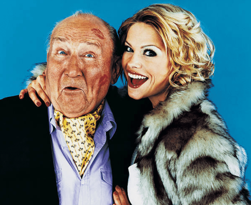 Blonde woman wearing fur coat kisses rich older man | Source: Getty Images