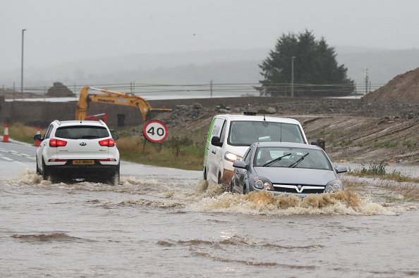 Des voitures se frayent un chemin sur une route inondée. |Photo : Getty : Images