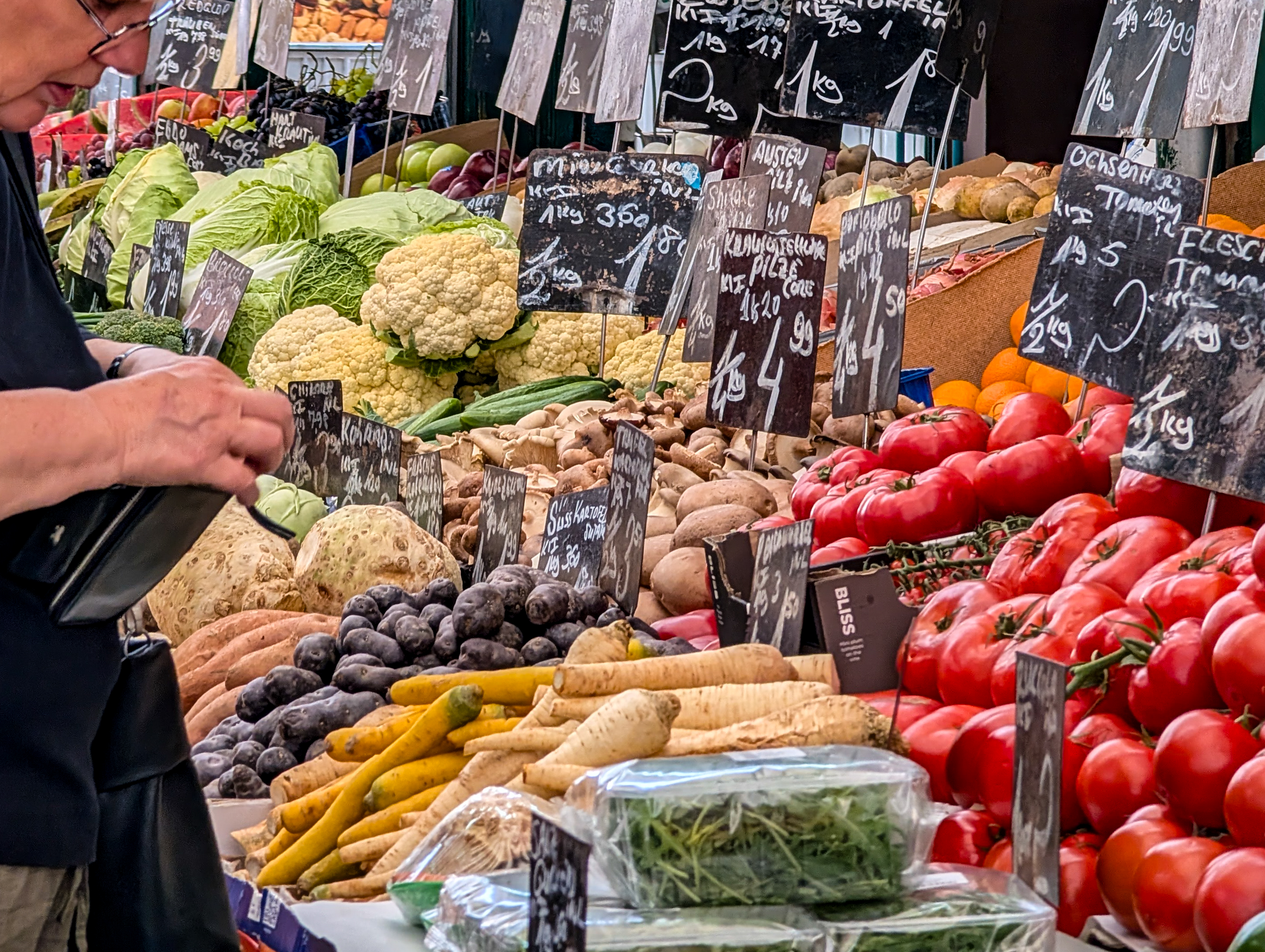 Fresh vegetables and handwritten price signs are displayed at a market stall | Source: Getty Images