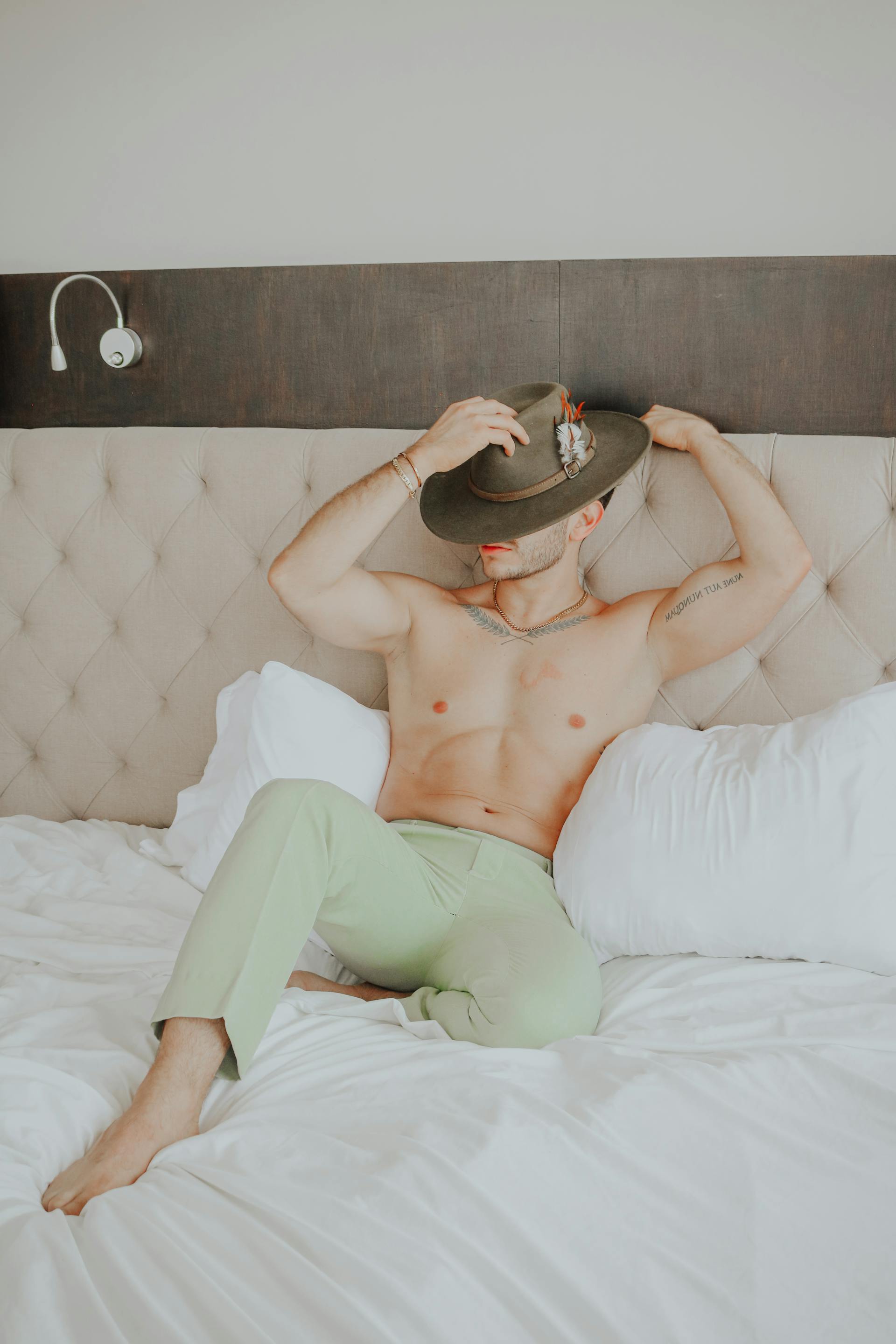 A man in green pants and a hat sitting on a bed | Source: Pexels