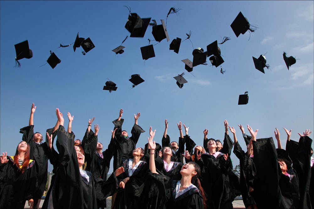Newly graduated students throwing hats up in the air | Source: Pexels