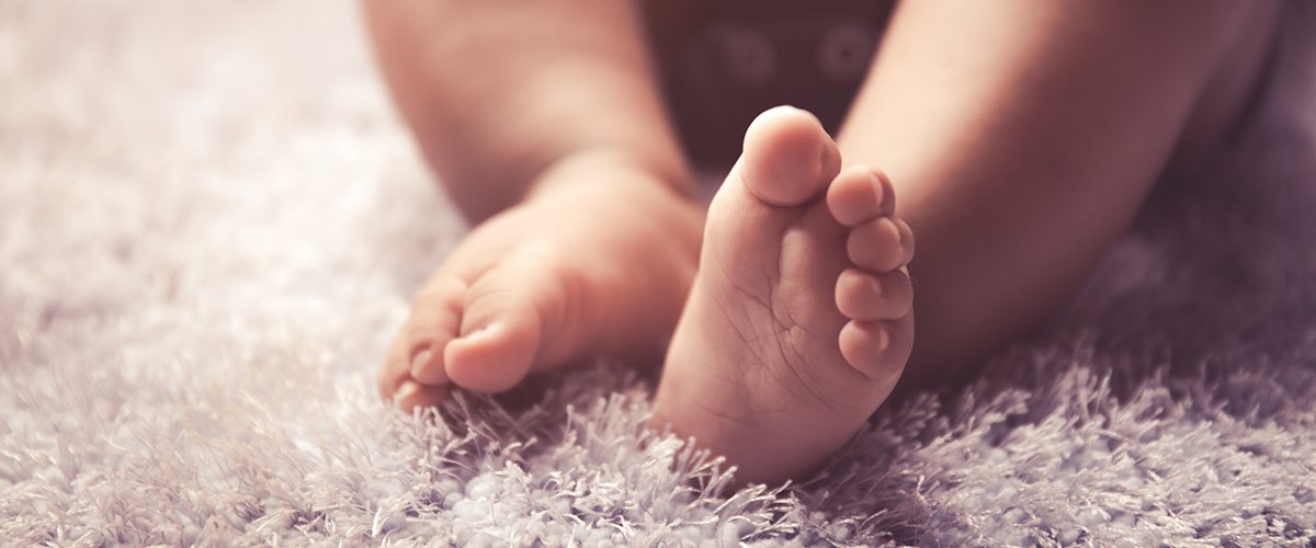 Die Füße eines Säuglings auf einem Teppich. | Quelle: Shutterstock  
