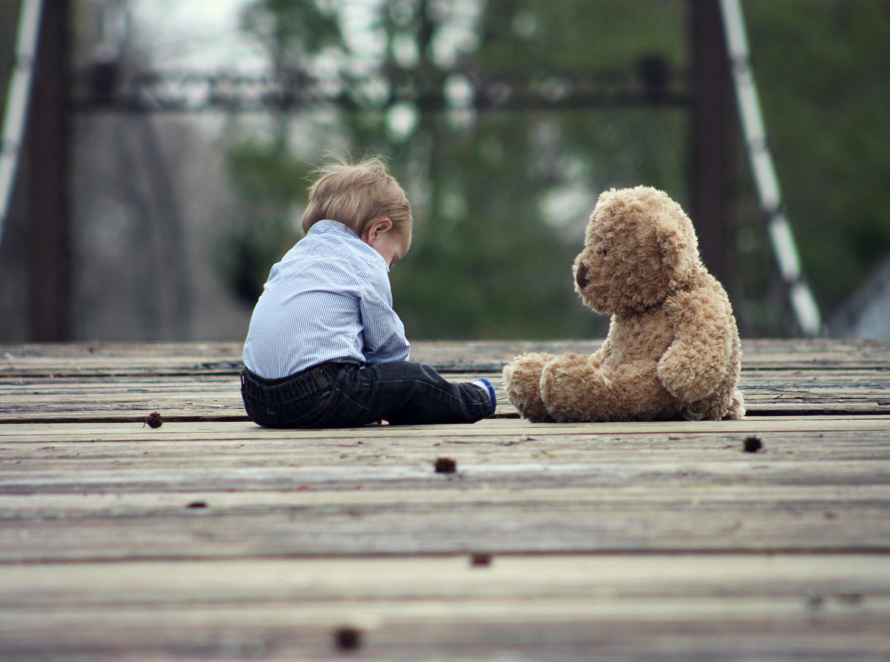 A sad child sitting next to a teddy bear | Source: Pexels