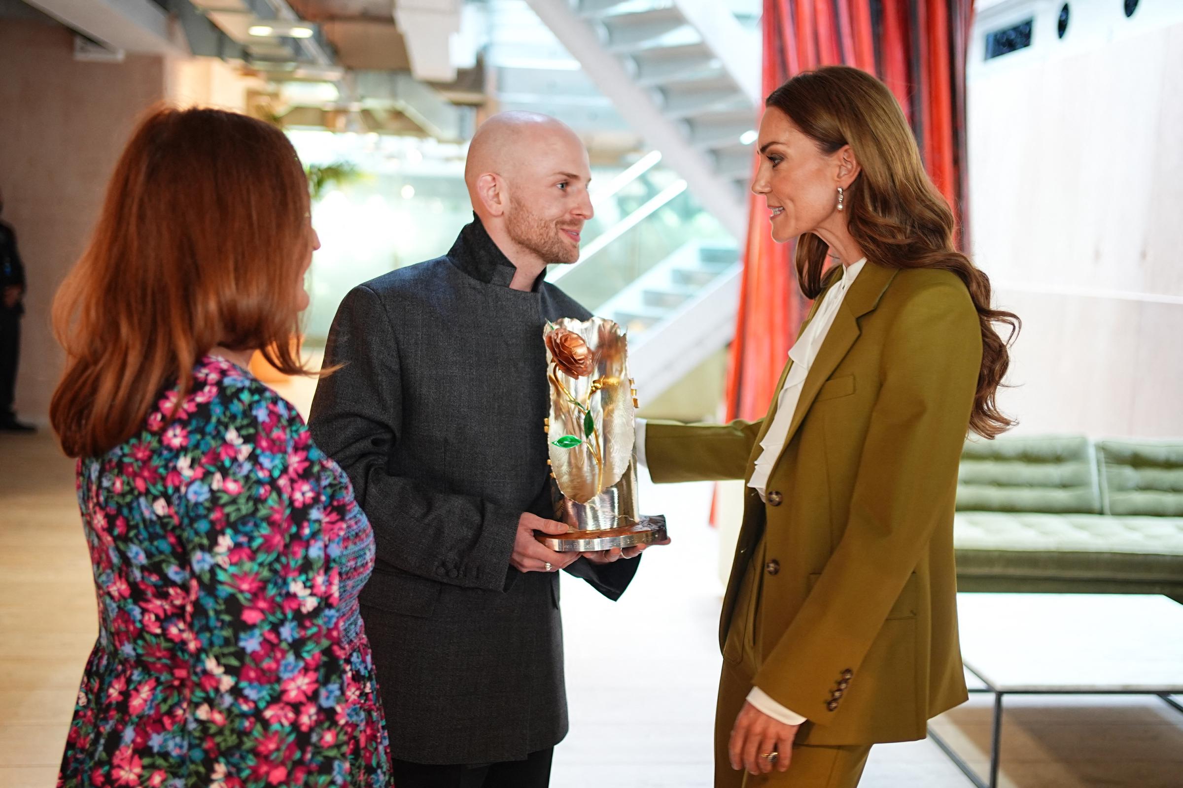 The trio share a light, joyful moment as they chat together—Catherine, Patrick McDowell, and his mother all engaged in warm conversation. Their expressions are relaxed and cheerful, radiating pride and excitement in celebration of Patrick’s achievement.