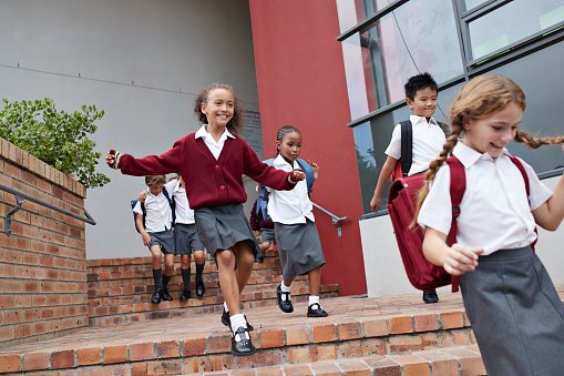 Photo of school children running and jumping off staircase from school building | Photo: Getty Images