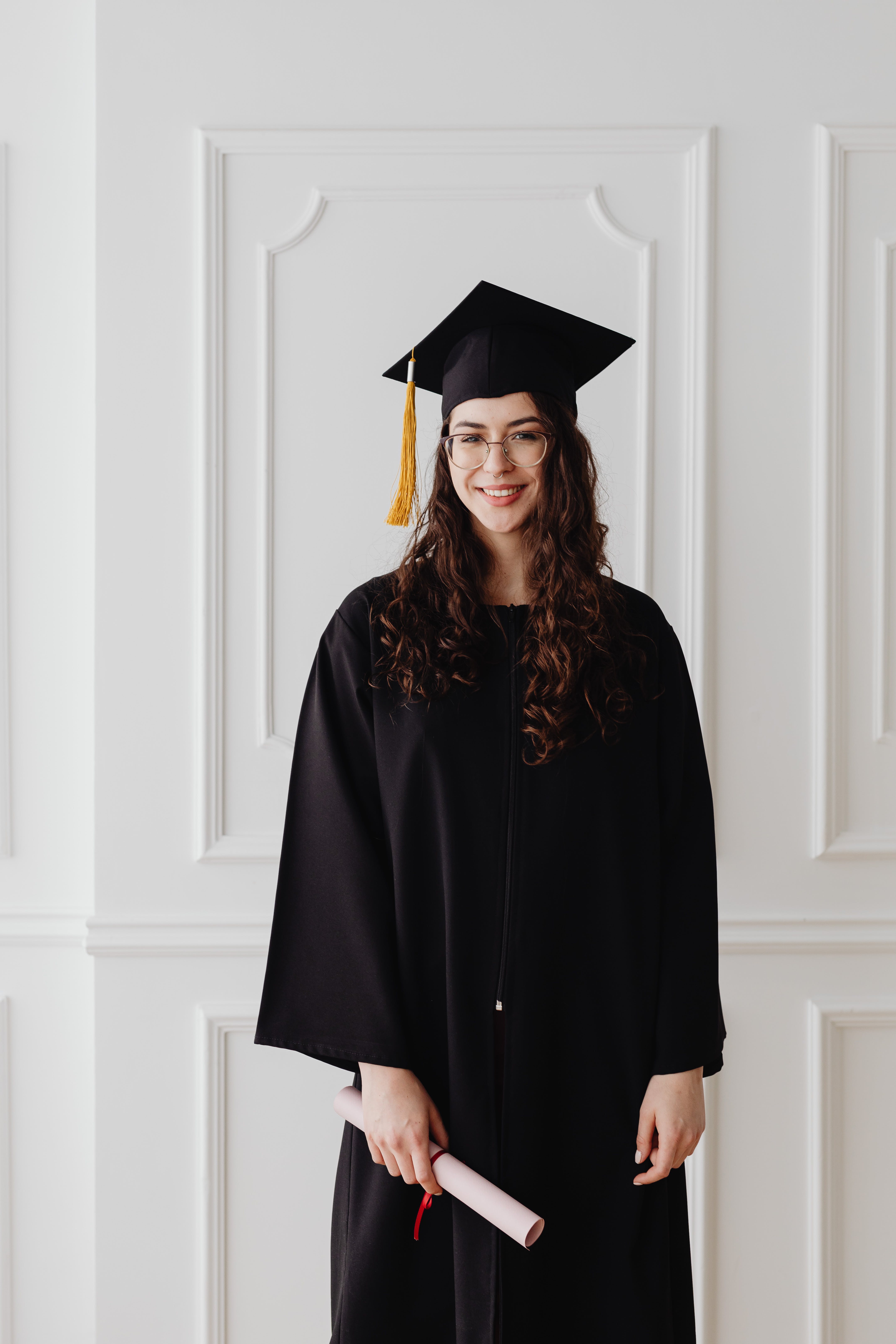 A woman smiles as she poses in graduation attire | Source: Pexels
