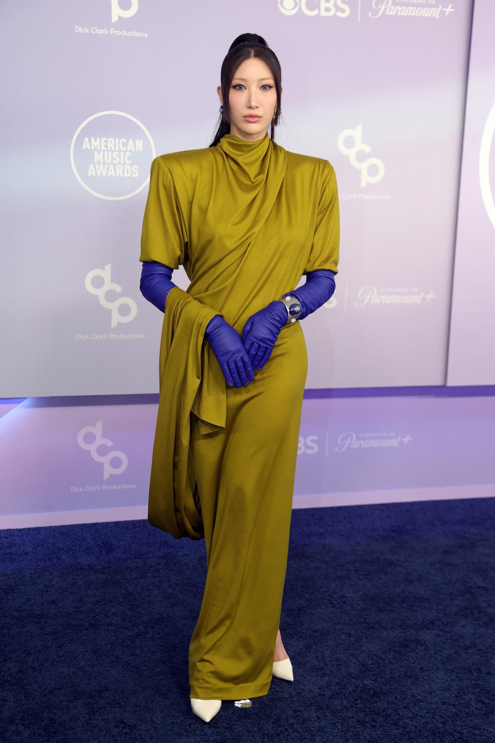 EJAE stands with matching blue gloves and sharp shoulder details that added contrast to the olive-green gown | Source: Getty Images