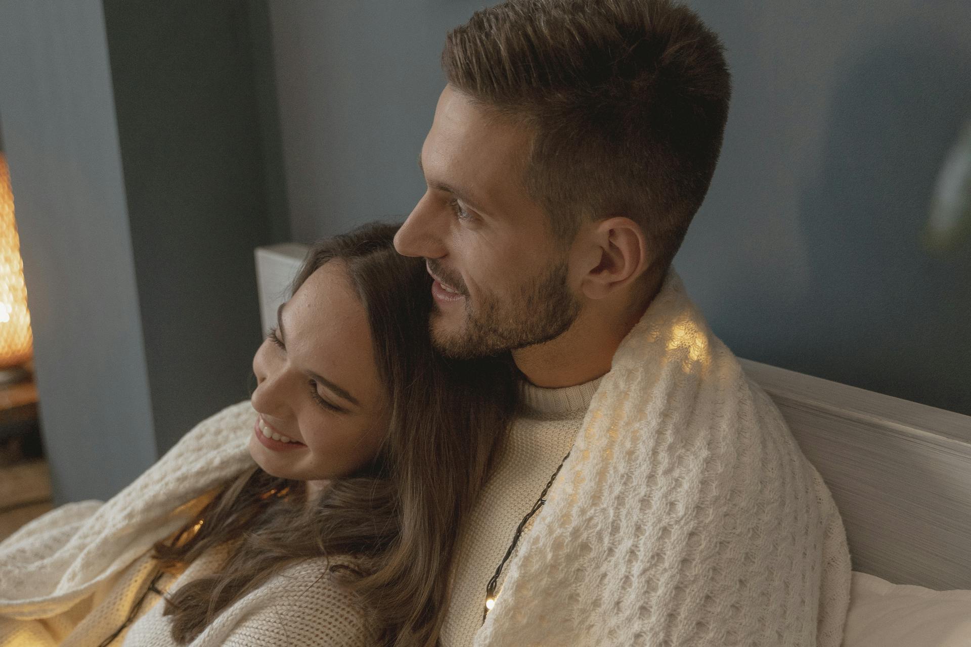 Close-up of a romantic couple sitting on the bed | Source: Pexels