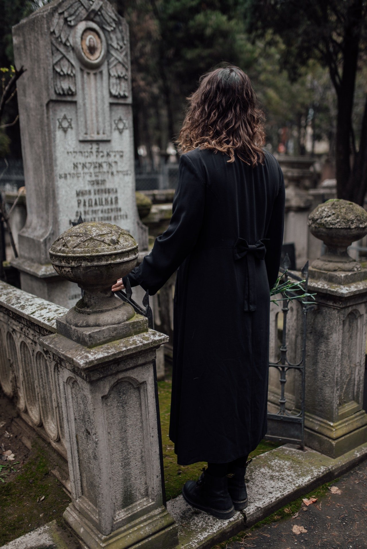Mujer parada frente a una tumba. | Foto: Pexels