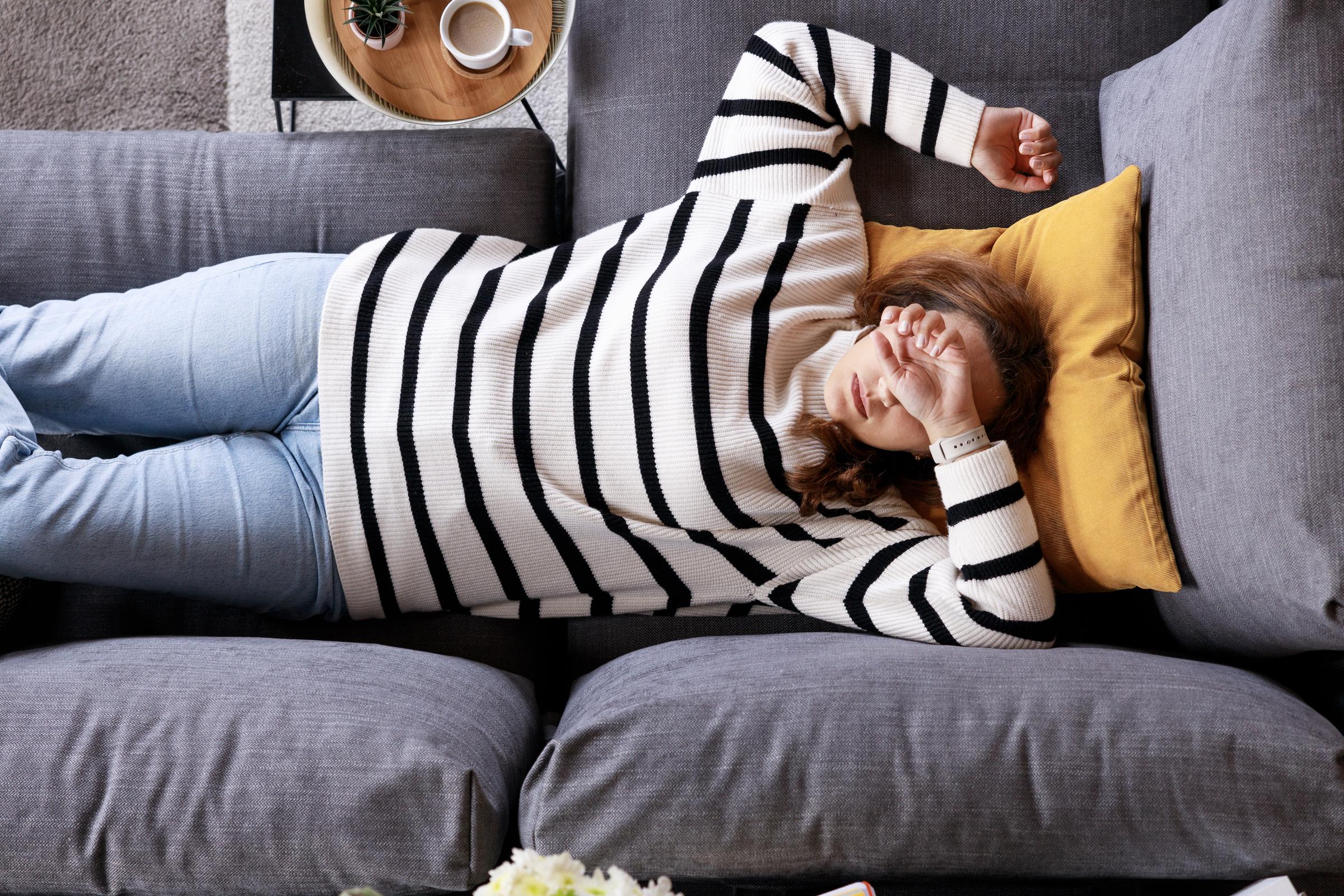 A tired woman lying on her couch | Source: Getty Images