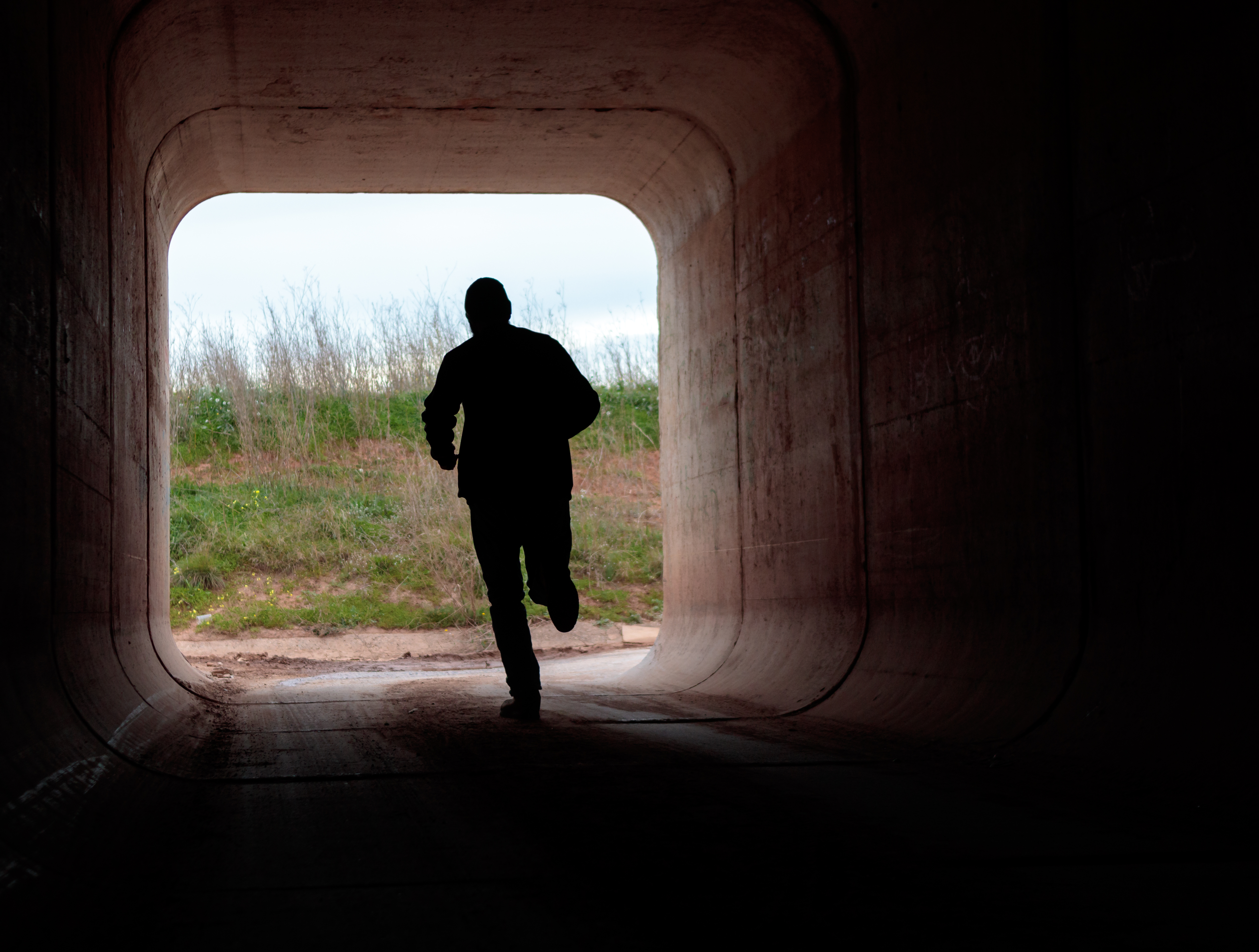 Man running through dark tunnel | Source: Shutterstock
