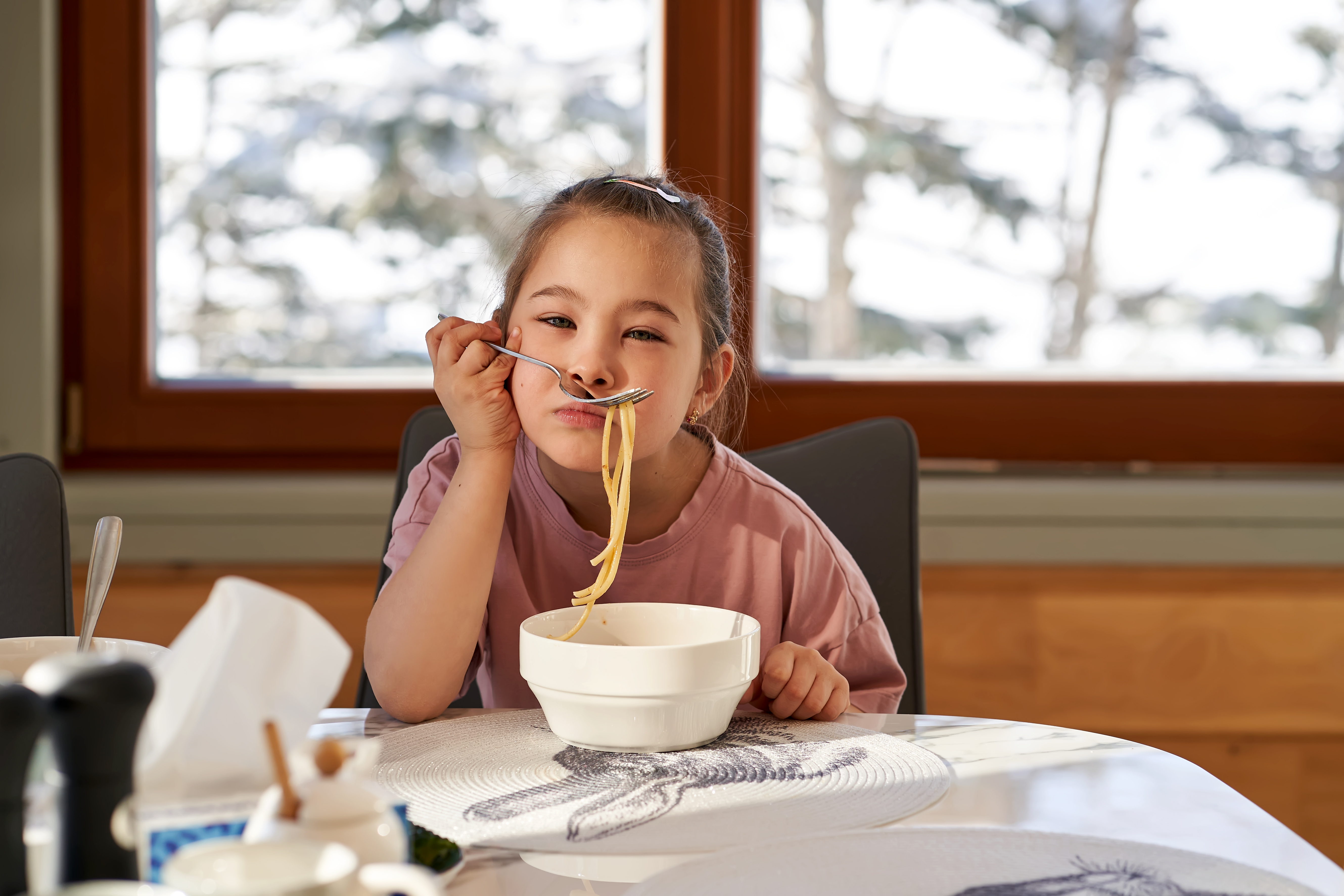 The girl tries on spaghetti like a mustache | Source: Getty Images