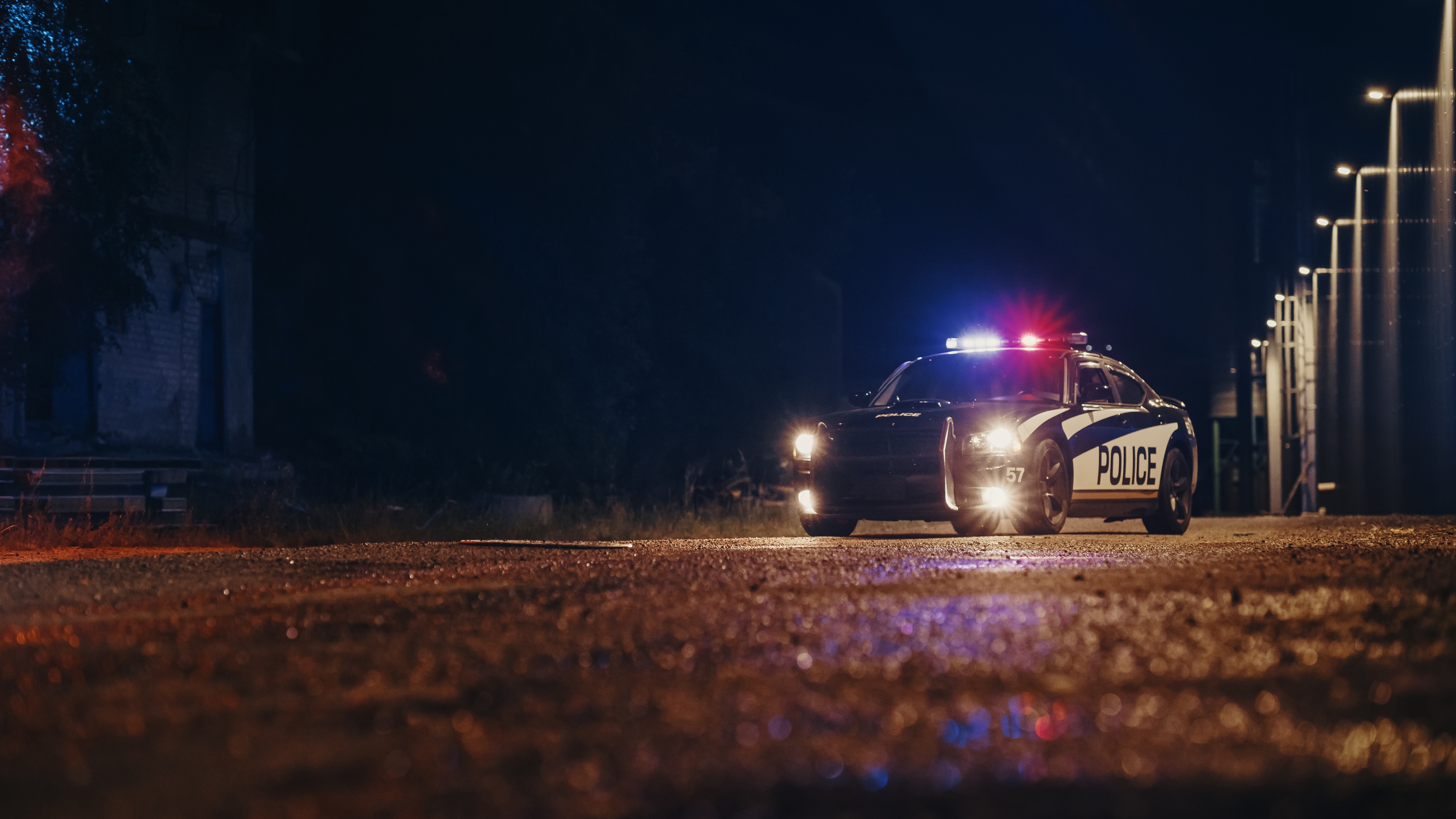 Low Angle Shot of a Stopped Police Car with Lights and Siren on During a Misty Night. Patrolling Vehicle on Stand by, Waiting for Orders to Start Pursuing Suspects. Police Enforcement | Source: Shutterstock