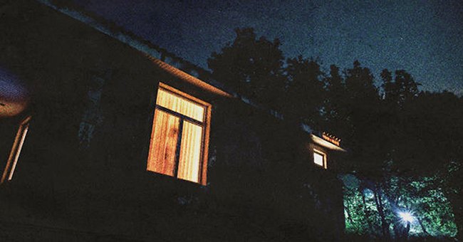 Light shines from a house window at night | Source: Shutterstock