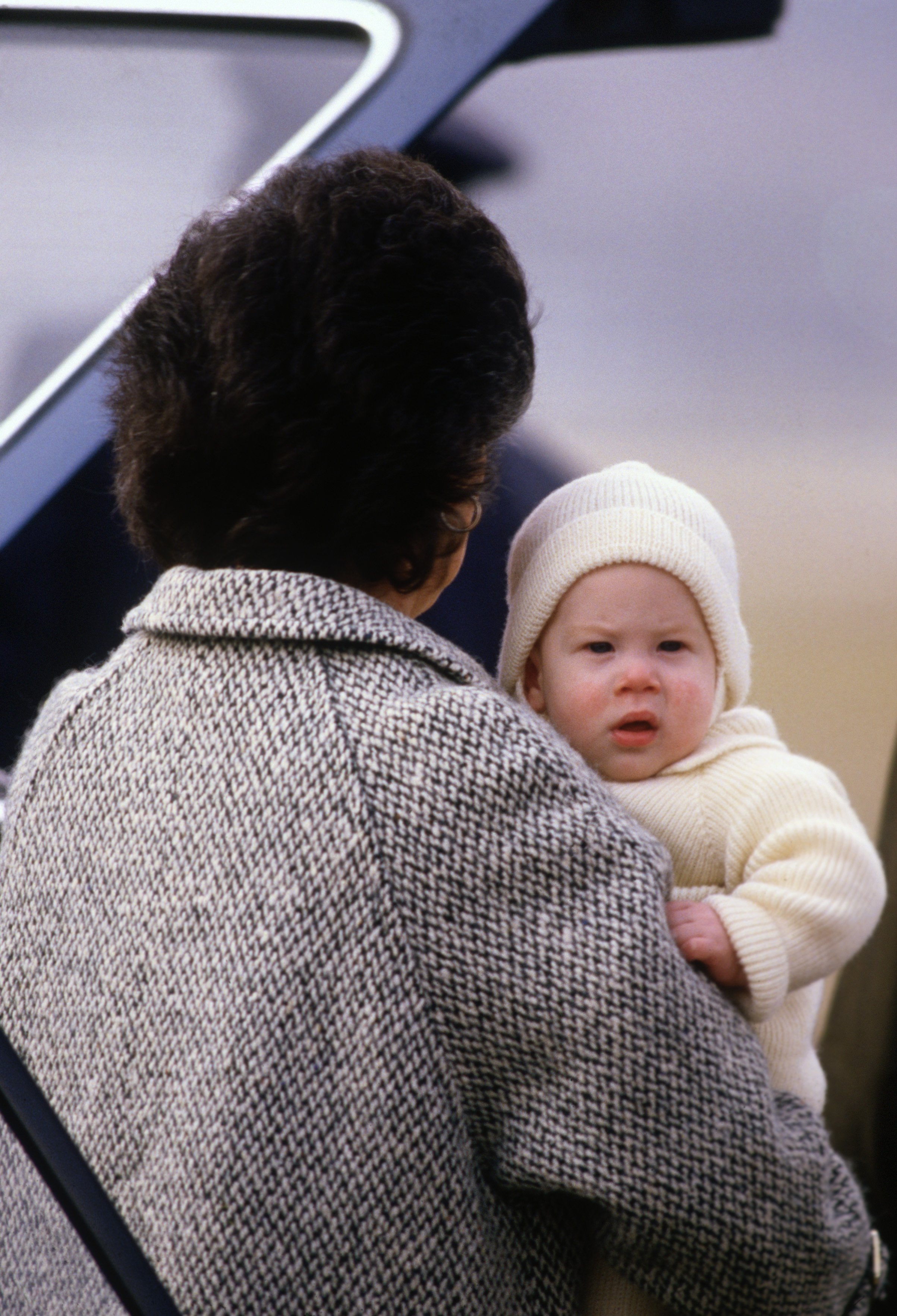 El Príncipe Harry en brazos de su niñera, Barbara Barnes, en marzo de 1985 en Aberdeen, Escocia || Fuente: Getty Images
