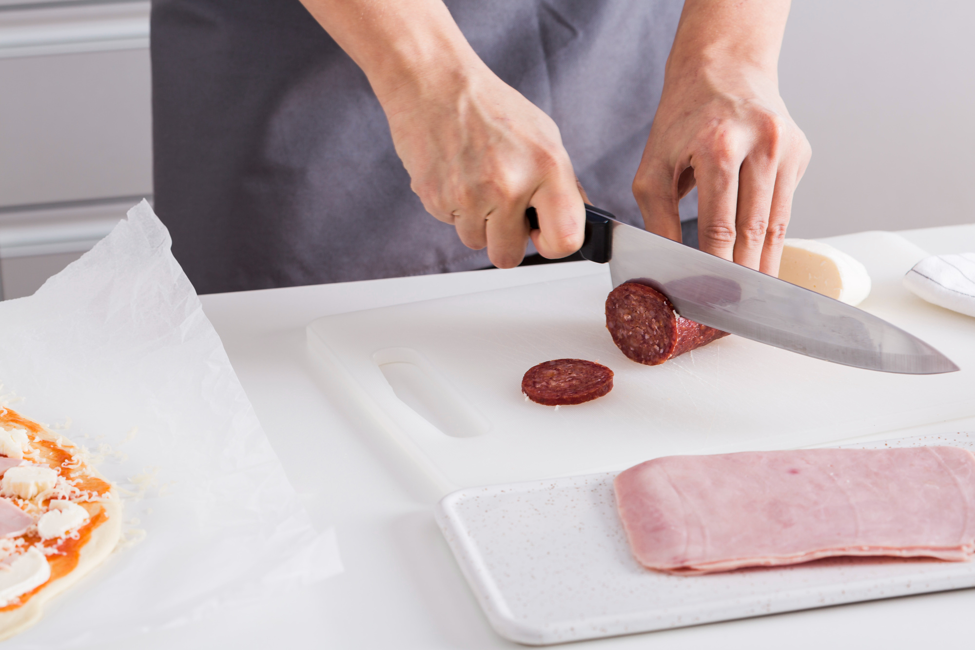 A woman cutting salami slices on a cutting board | Source: Freepik