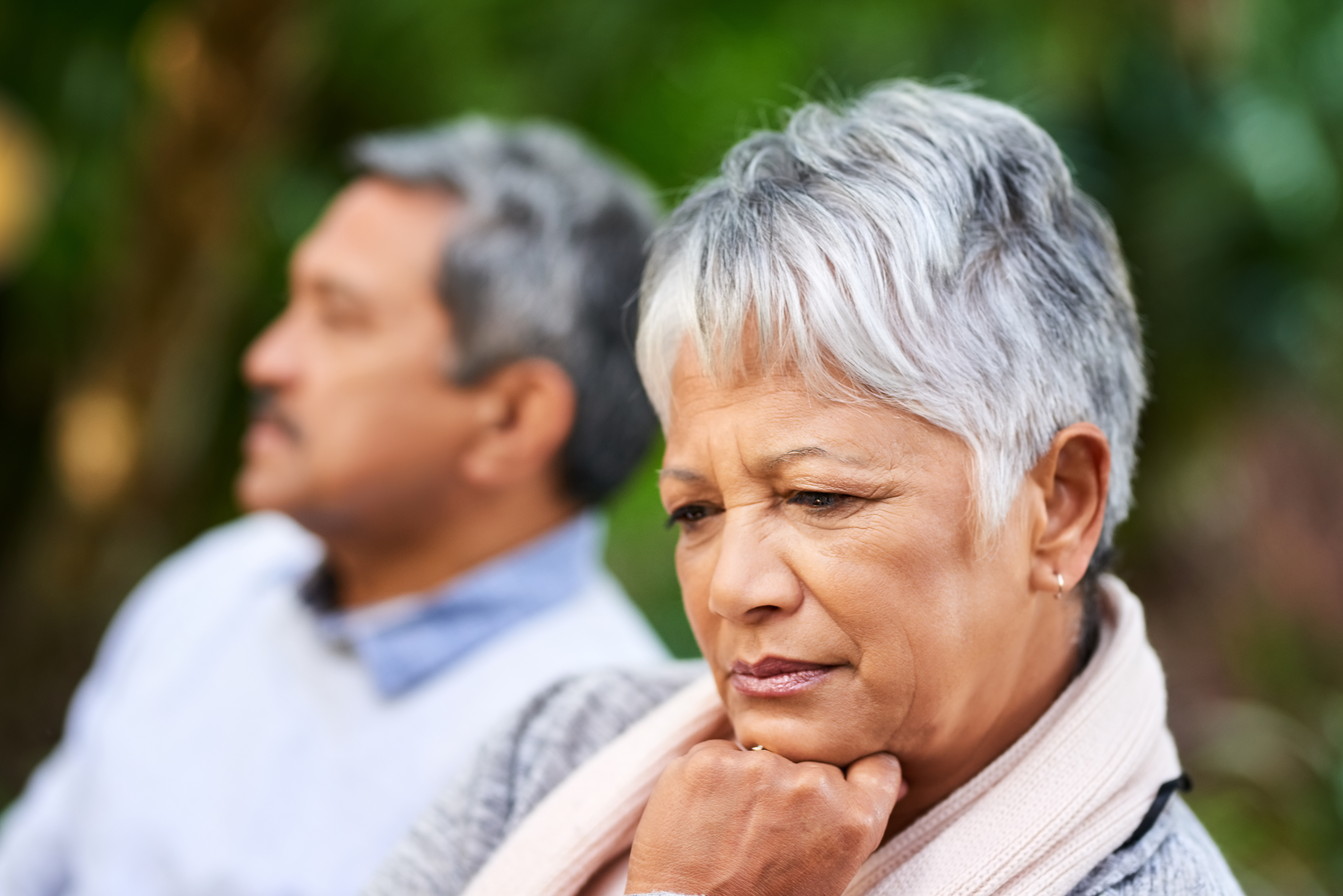 An upset older woman looking to the side while a man sits closeby | Source: Getty Images