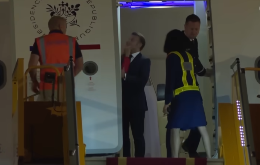 President Emmanuel Macron comes into view after the door to their plane opened | Source: YouTube/The Guardian