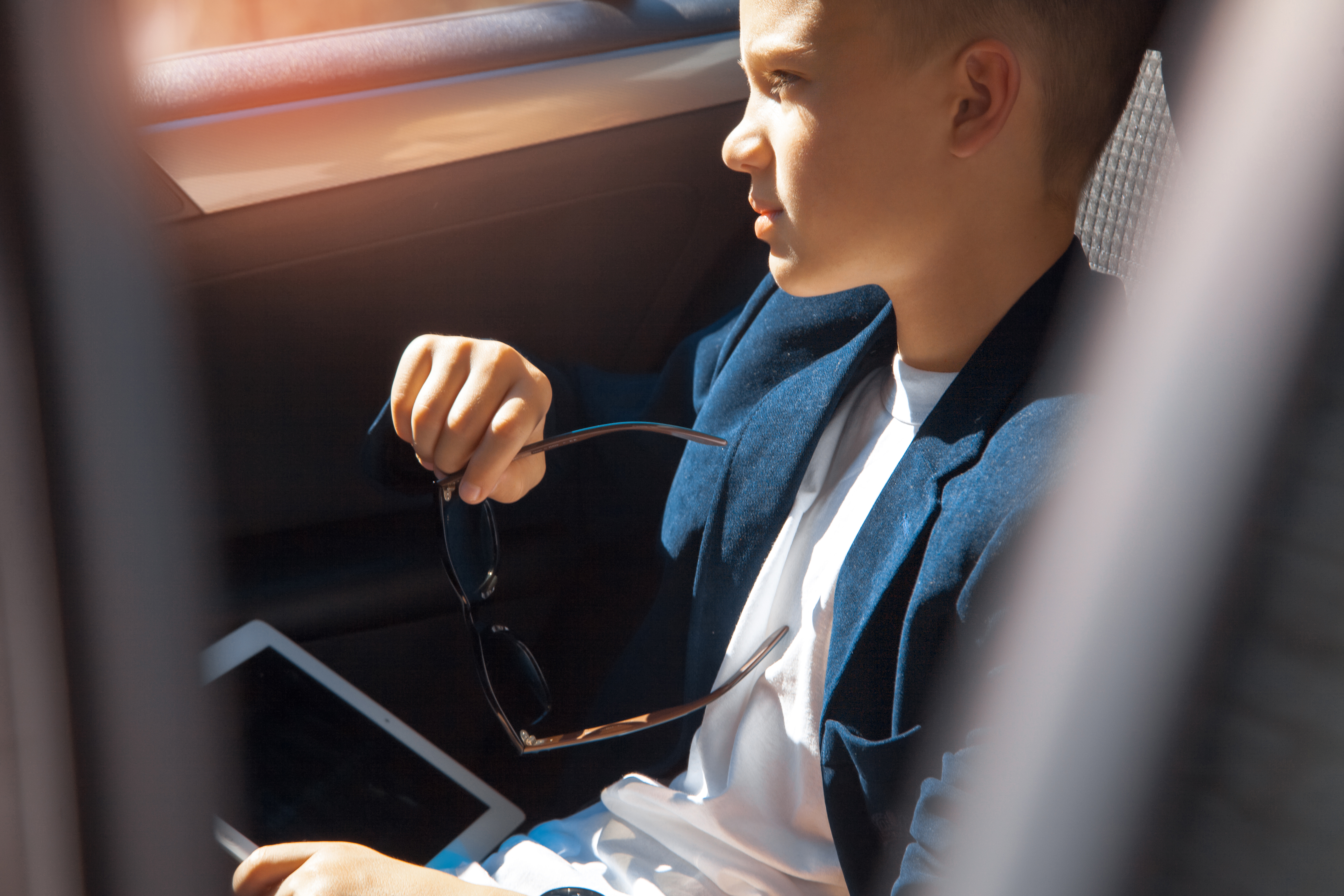Young rich boy sits on a backseat of car. | Source: Shutterstock