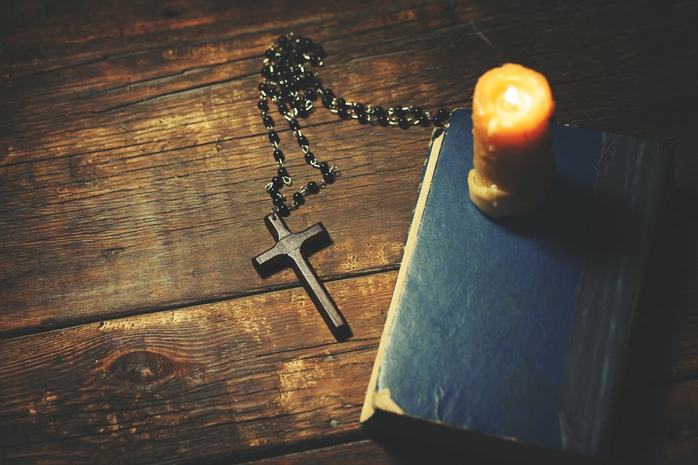 Biblia, rosario y una vela encendida.| Fuente: Shutterstock Biblia, rosario y una vela encendida.| Fuente: Shutterstock