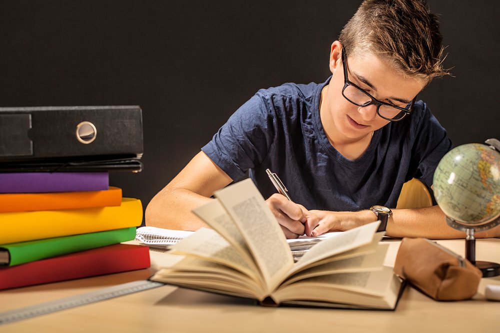 Joven estudiando rodeado de libros. | Foto: Shutterstock