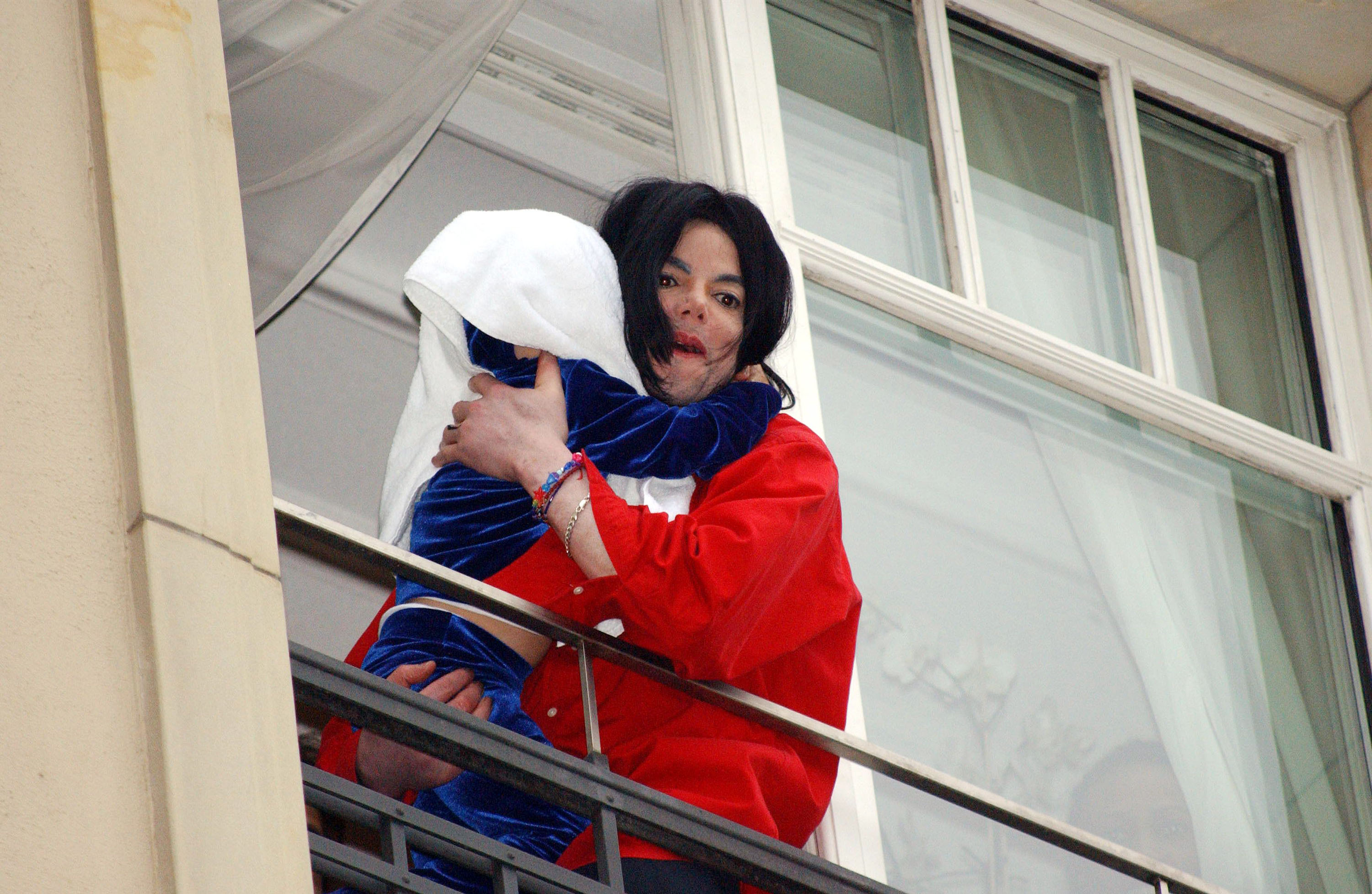 Michael Jackson holding one of his kids while on a balcony in Berlin, Germany on November 19, 2002 | Source: Getty Images