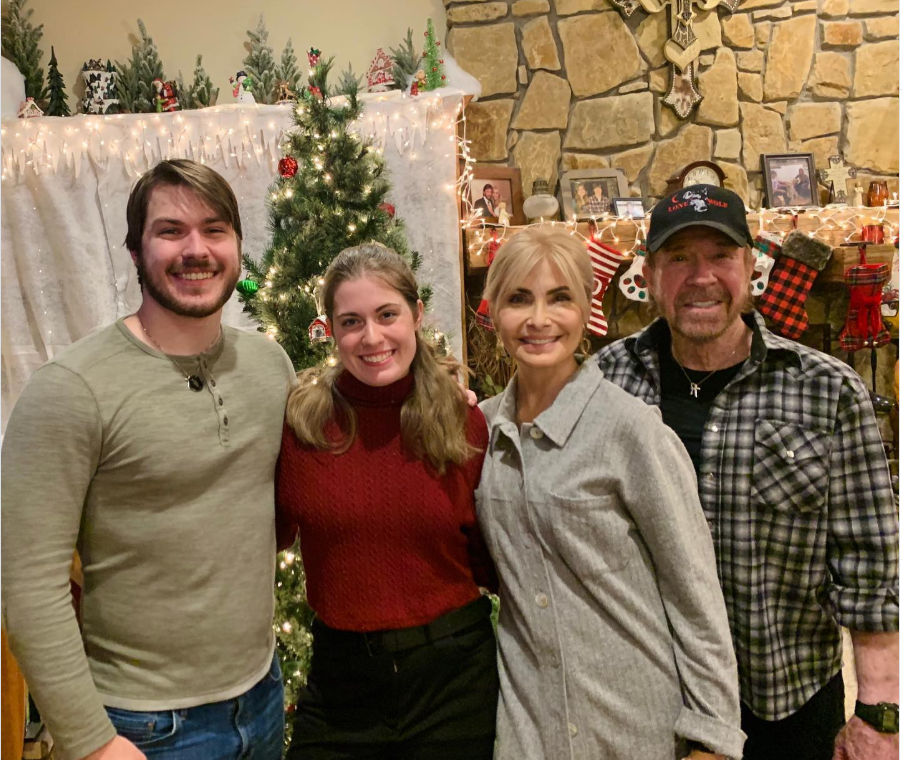 By a glowing Christmas tree, Chuck Norris, Gena O'Kelley Norris, Danilee Norris, and Dakota Norris share a warm holiday moment, sending festive cheer and family love. | Source: Instagram/chucknorris