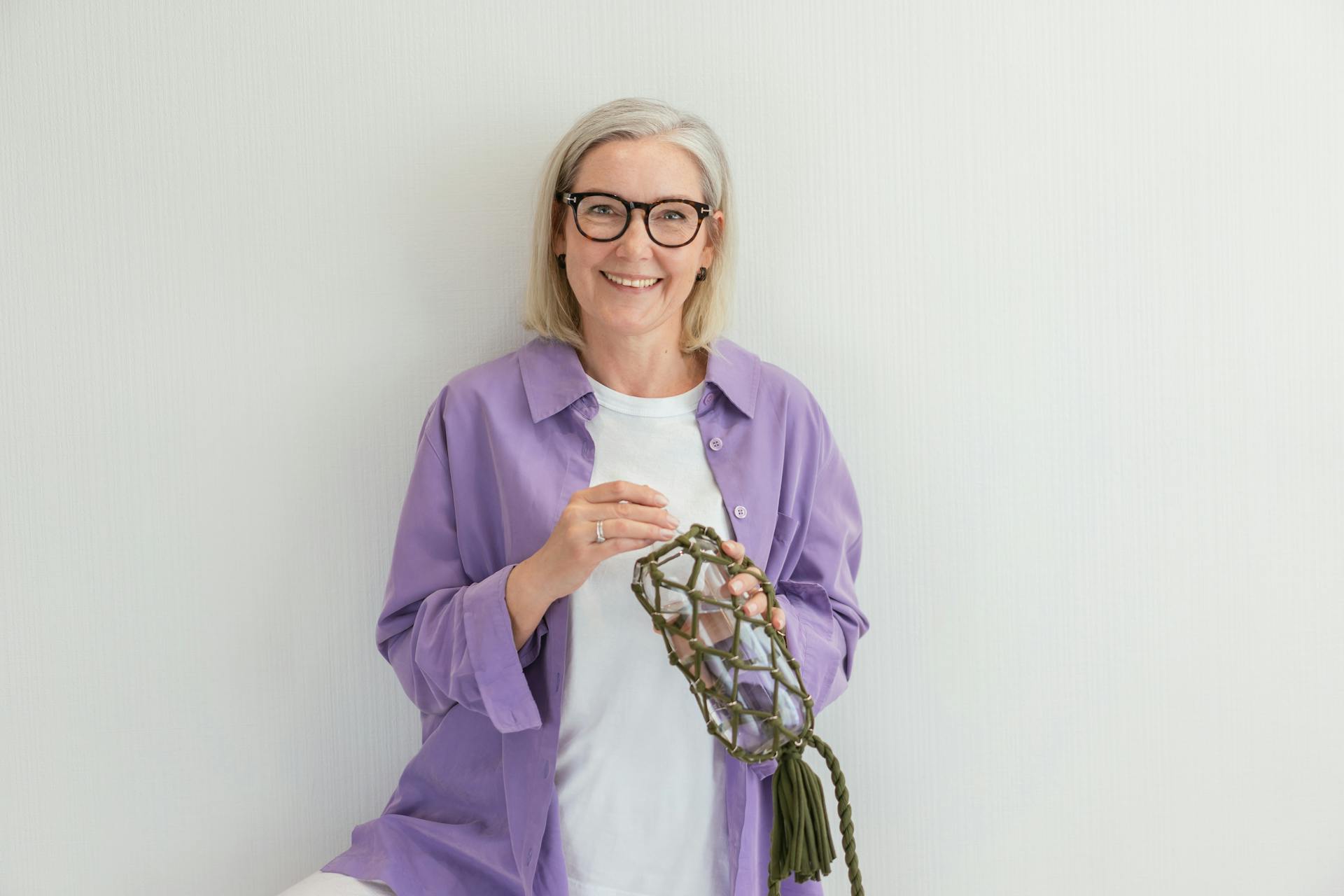 A smiling old woman holding a bottle | Source: Pexels
