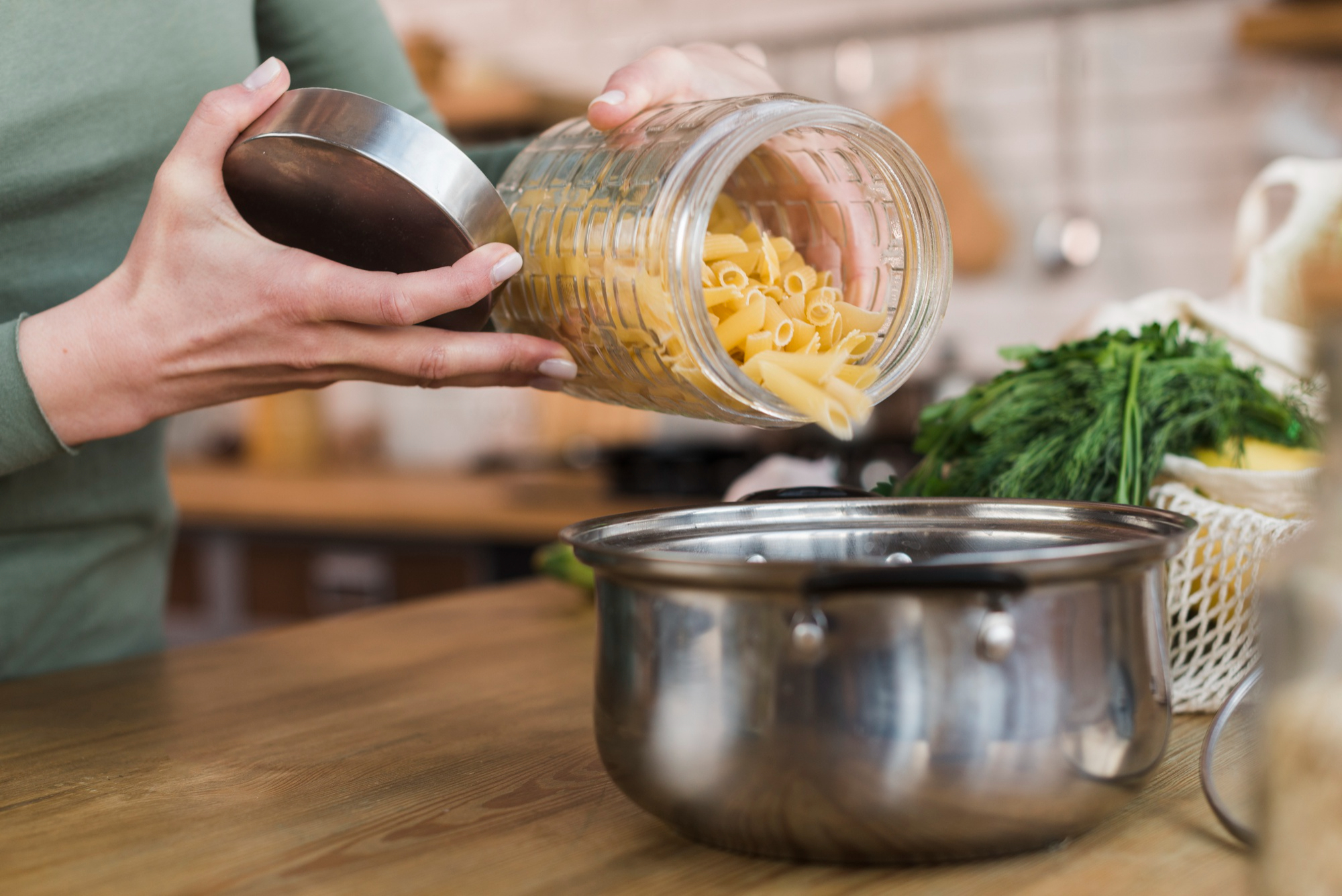 A woman pouring raw pasta in a pot | Source: Freepik