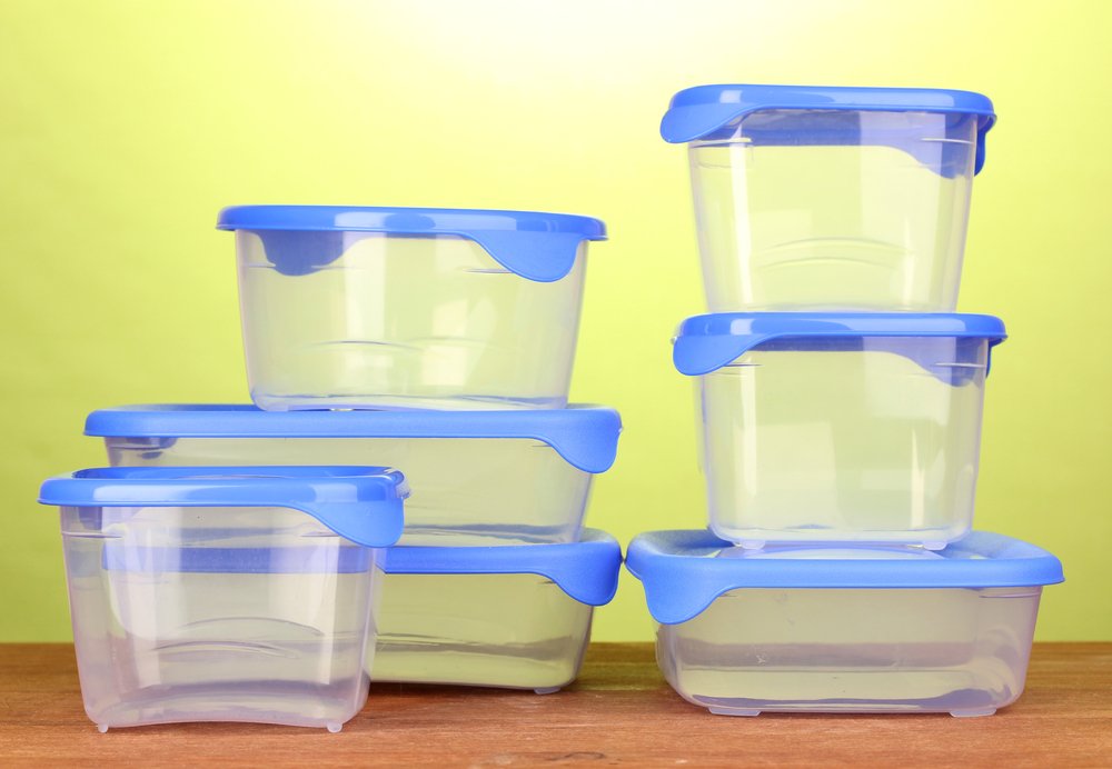 Boîtes en plastique sur une table en bois sur fond vert | Photo : Shutterstock