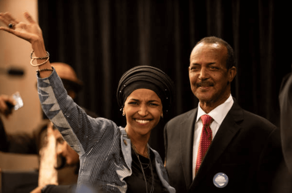 Ilhan Omar waves to supporters while standing with her father Nur Omar Mohamed on November 6, 2018, in Minneapolis, Minnesota | Source: Stephen Maturen/Getty Images