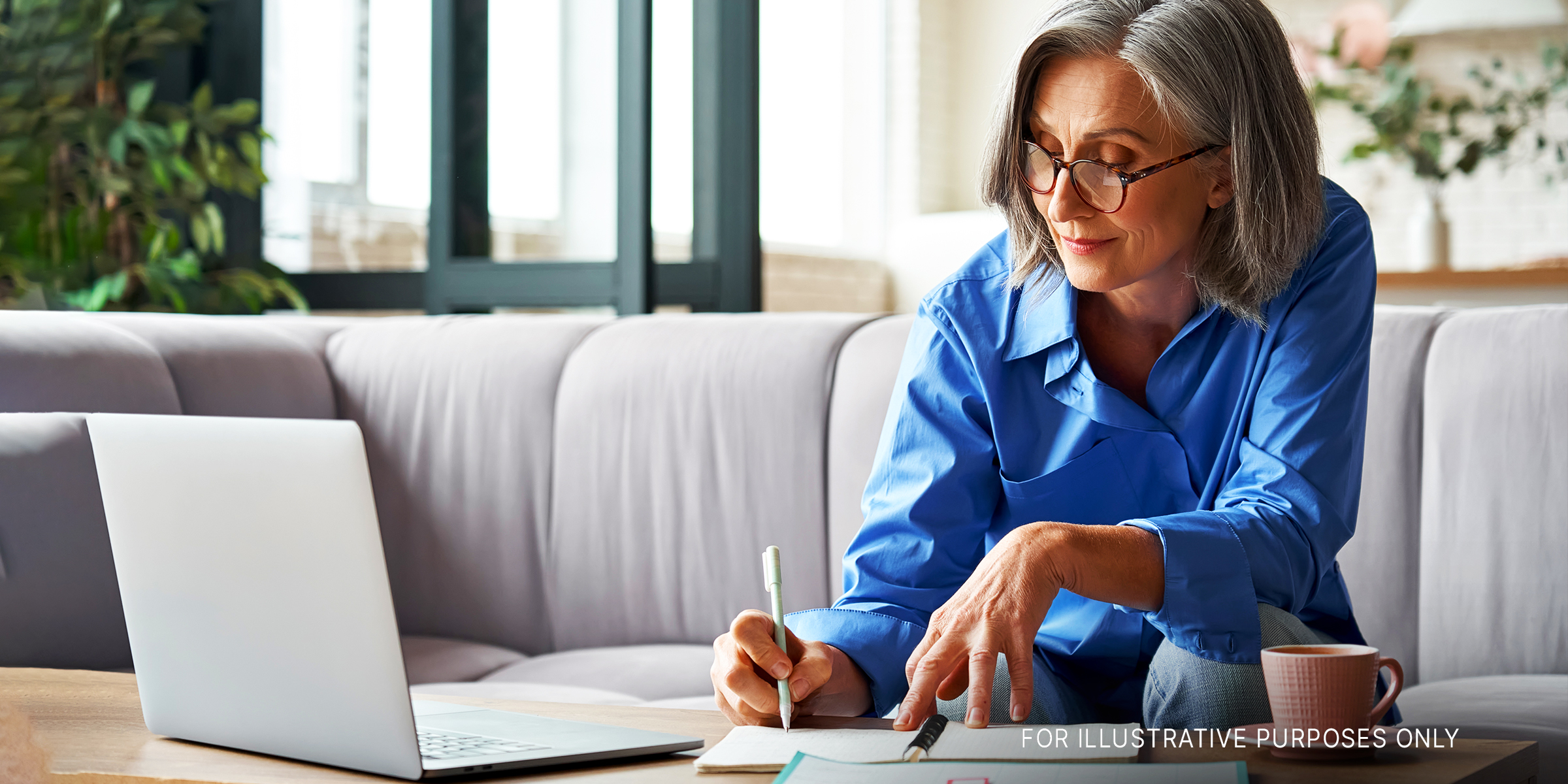 A senior lady taking notes while working on a laptop | Source: Shutterstock