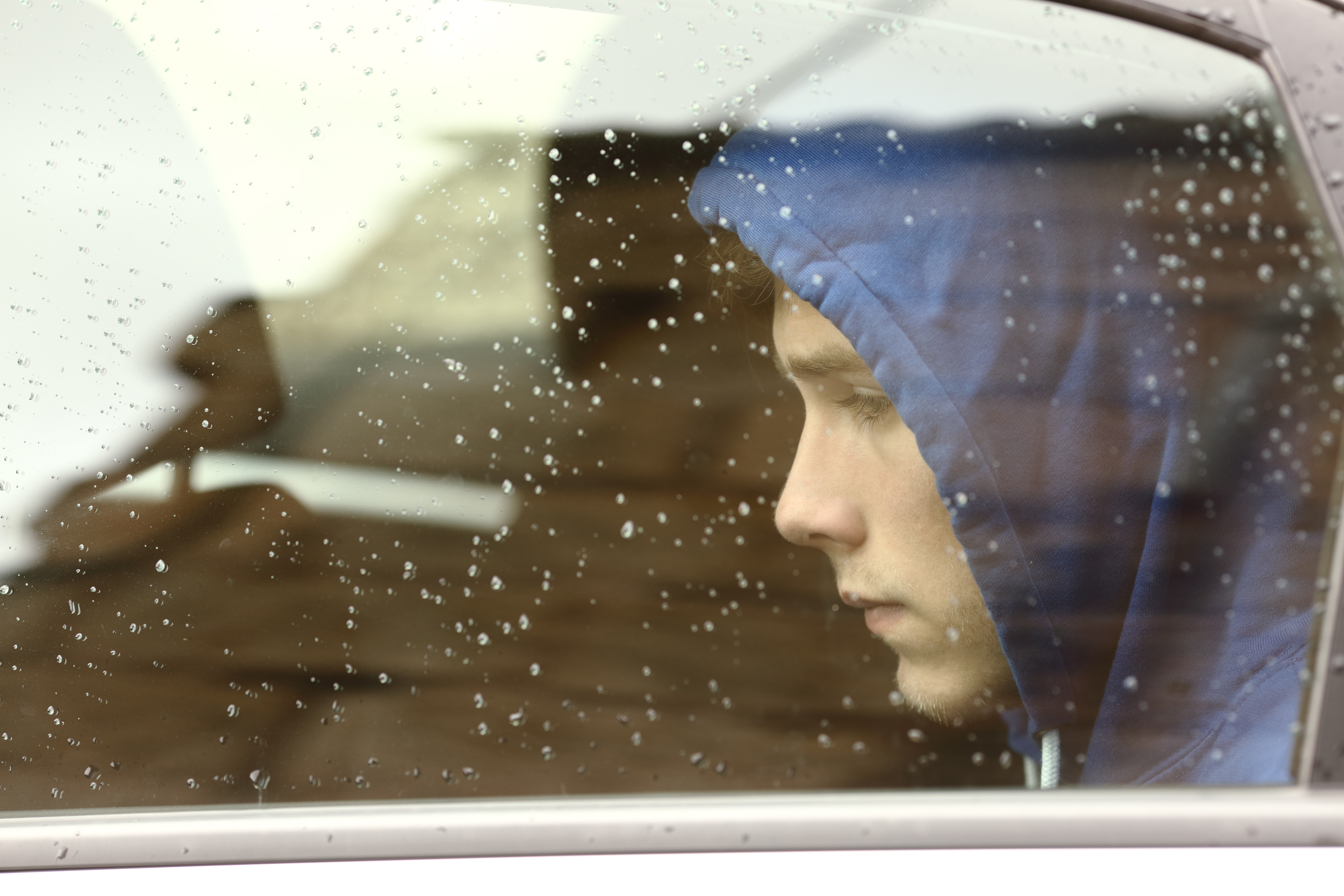 A sad teenage boy looks out through the car window | Source: Shutterstock