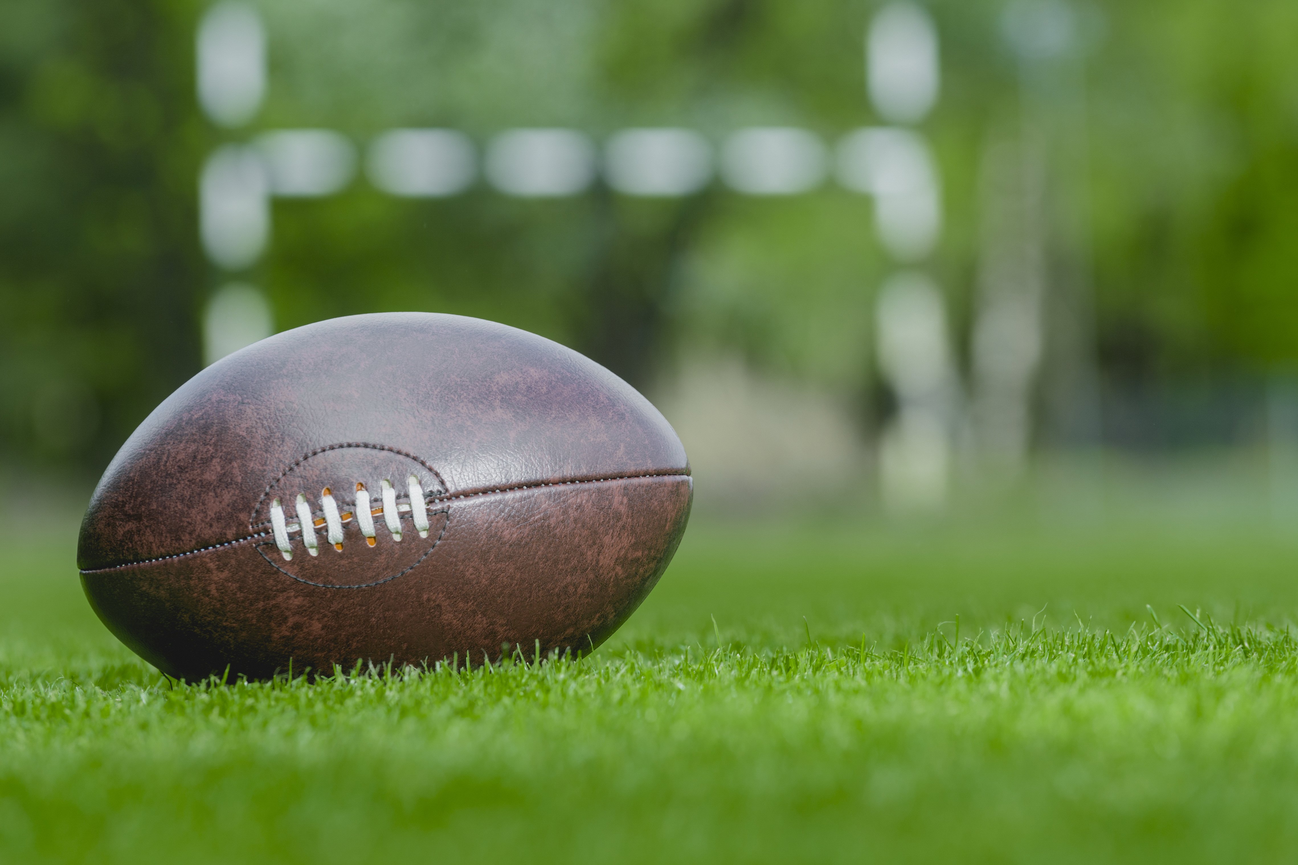 American football, rugby ball on a green grass field background. | Photo: Getty images