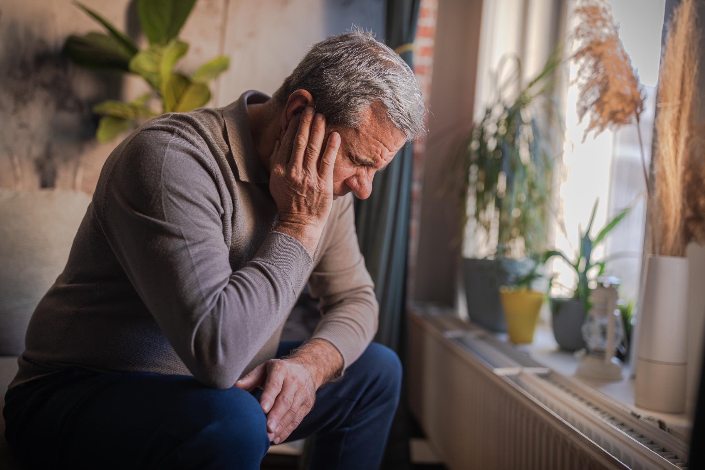 Man sitting and holding his ear in pain from a severe earache | Source: Getty Images