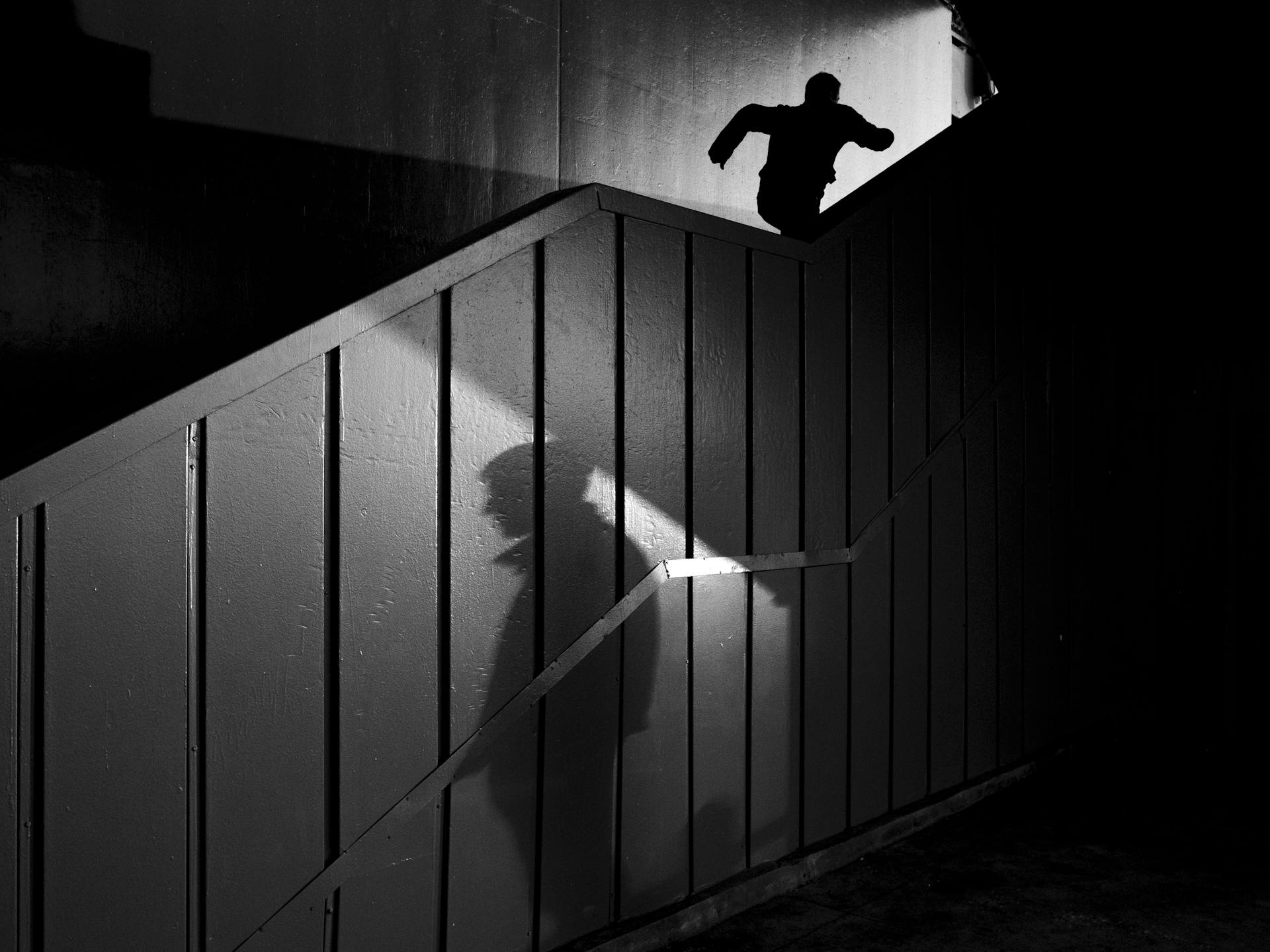 Silhouette of a man's shadow and another man running upstairs | Source: Pexels