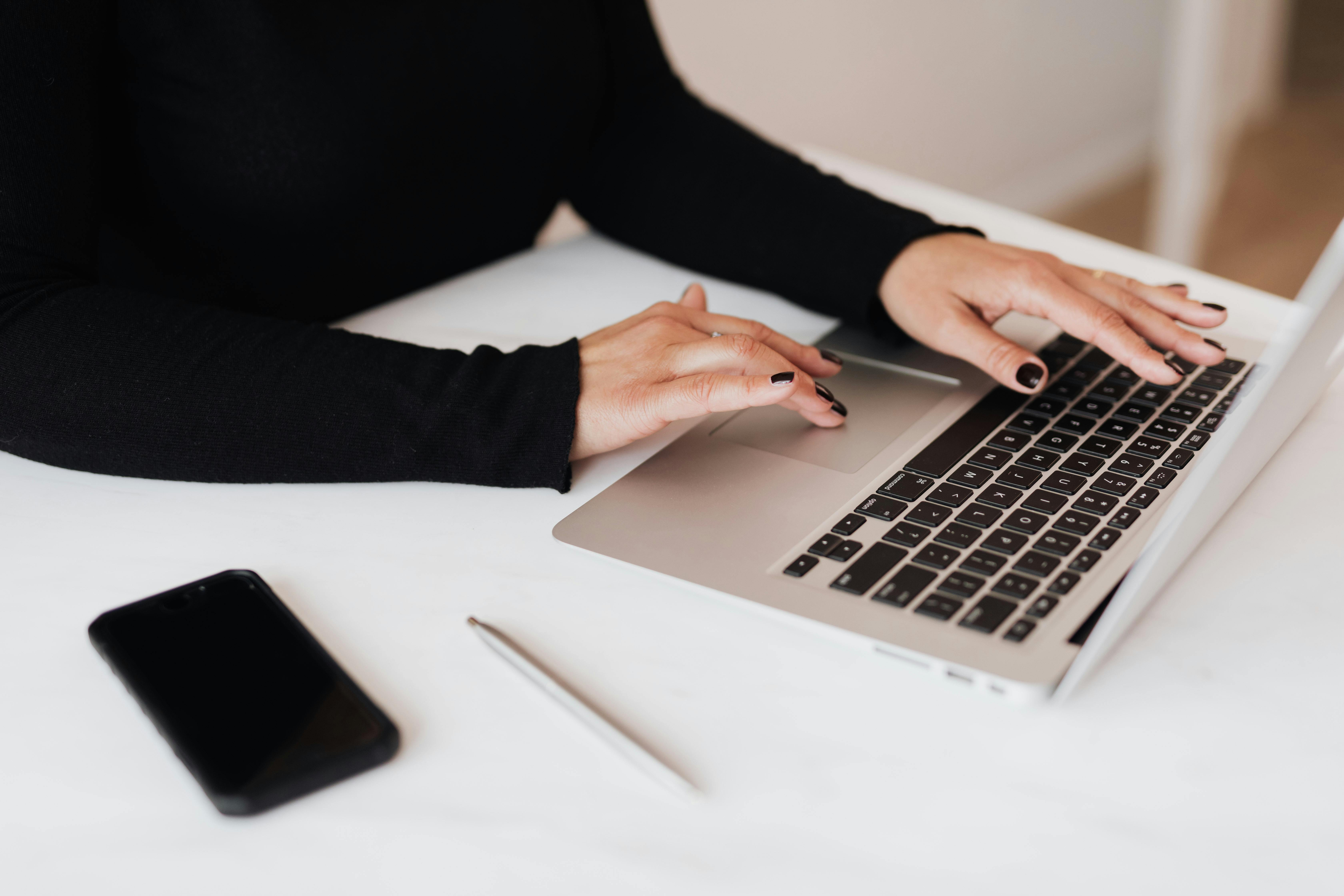 A woman using her laptop with her phone nearby | Source: Pexels