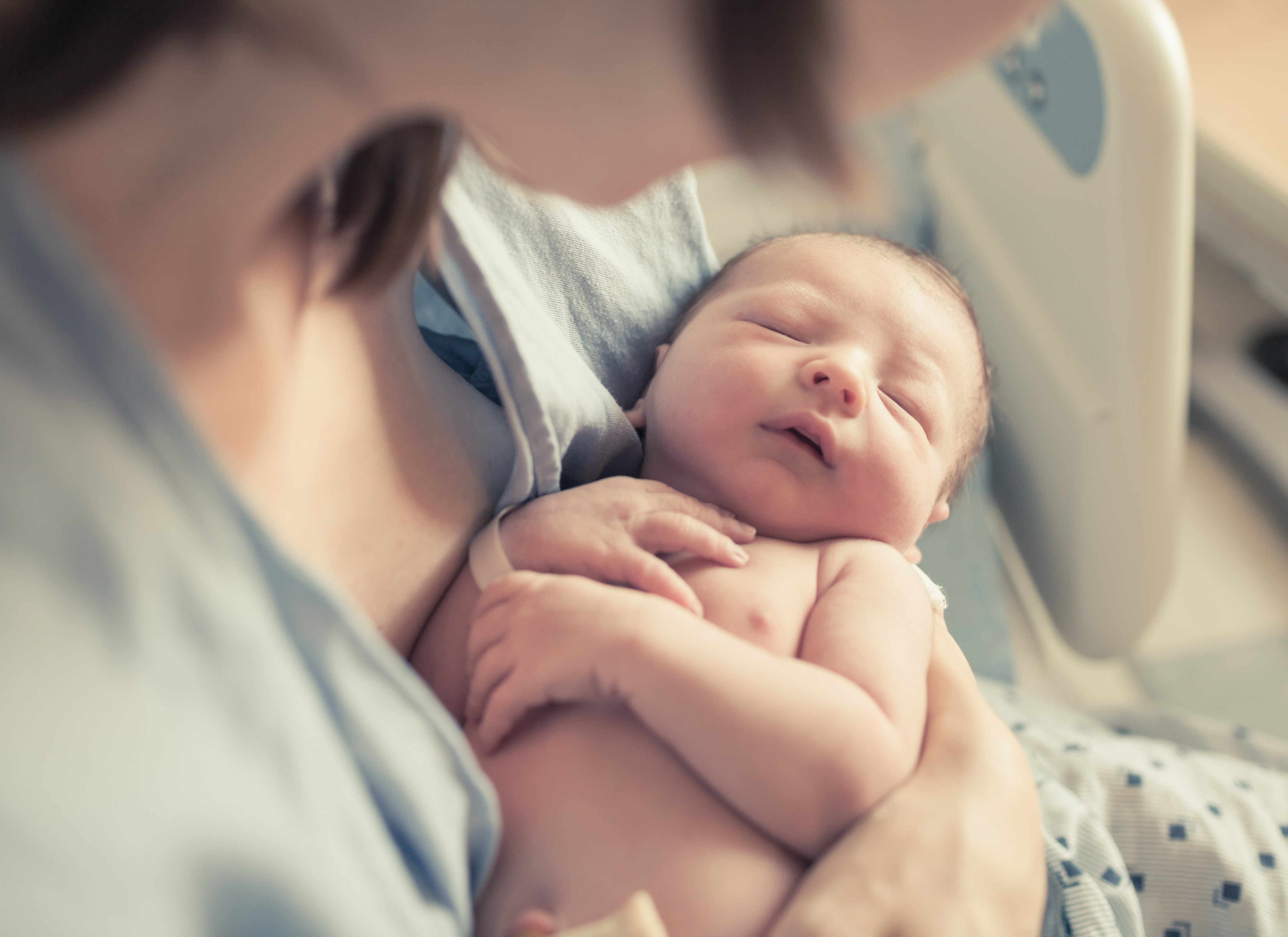 A close-up photo of a woman holding her newborn baby | Source: Shutterstock