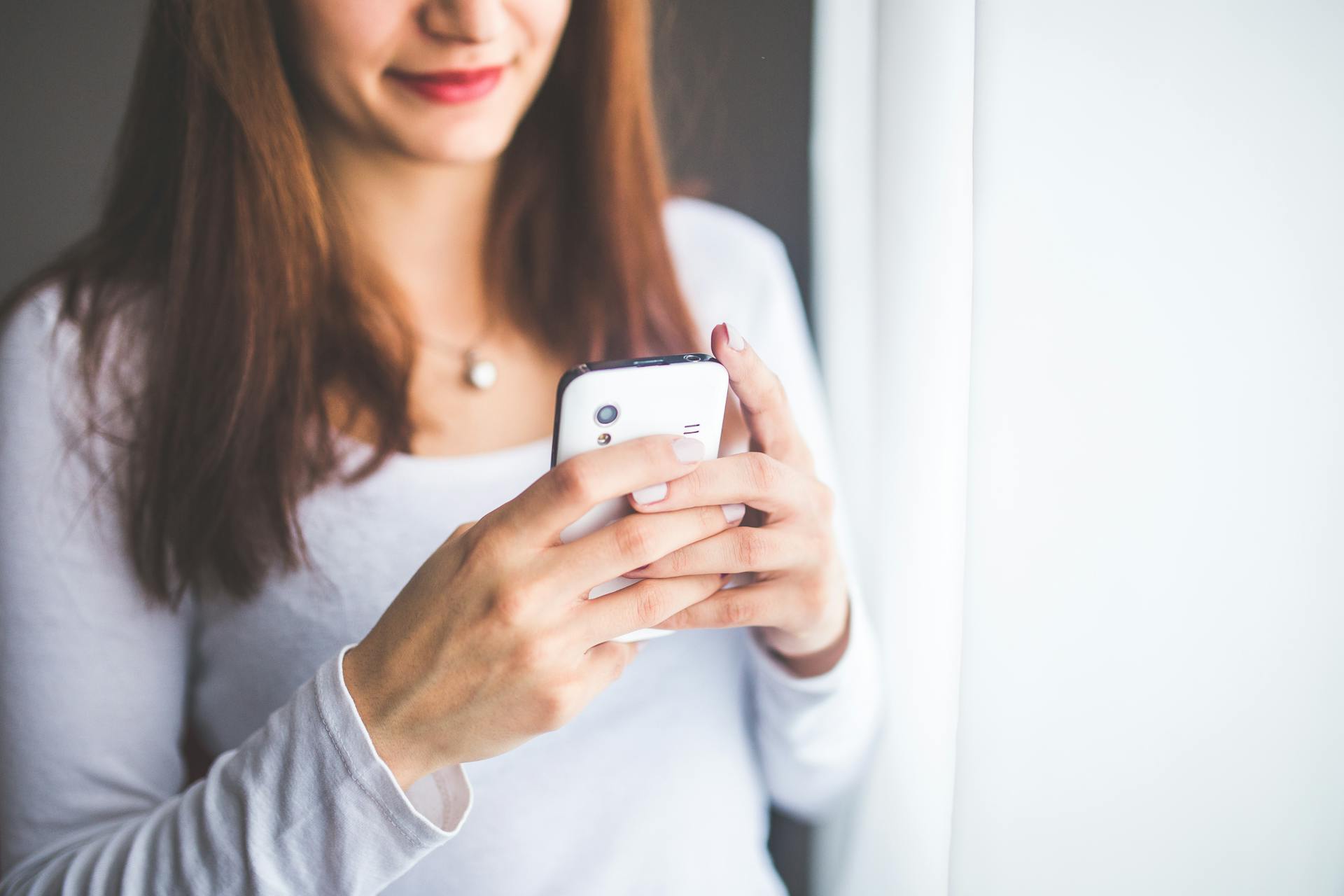 A woman holding a white smartphone | Source: Pexels