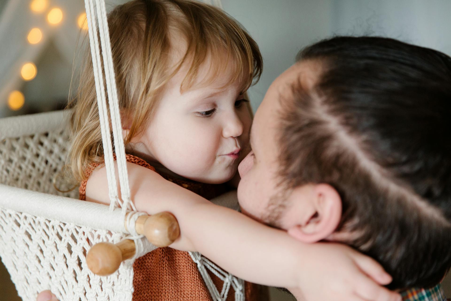 A little girl hugging her father while resting in a hanging swing | Source: Pexels