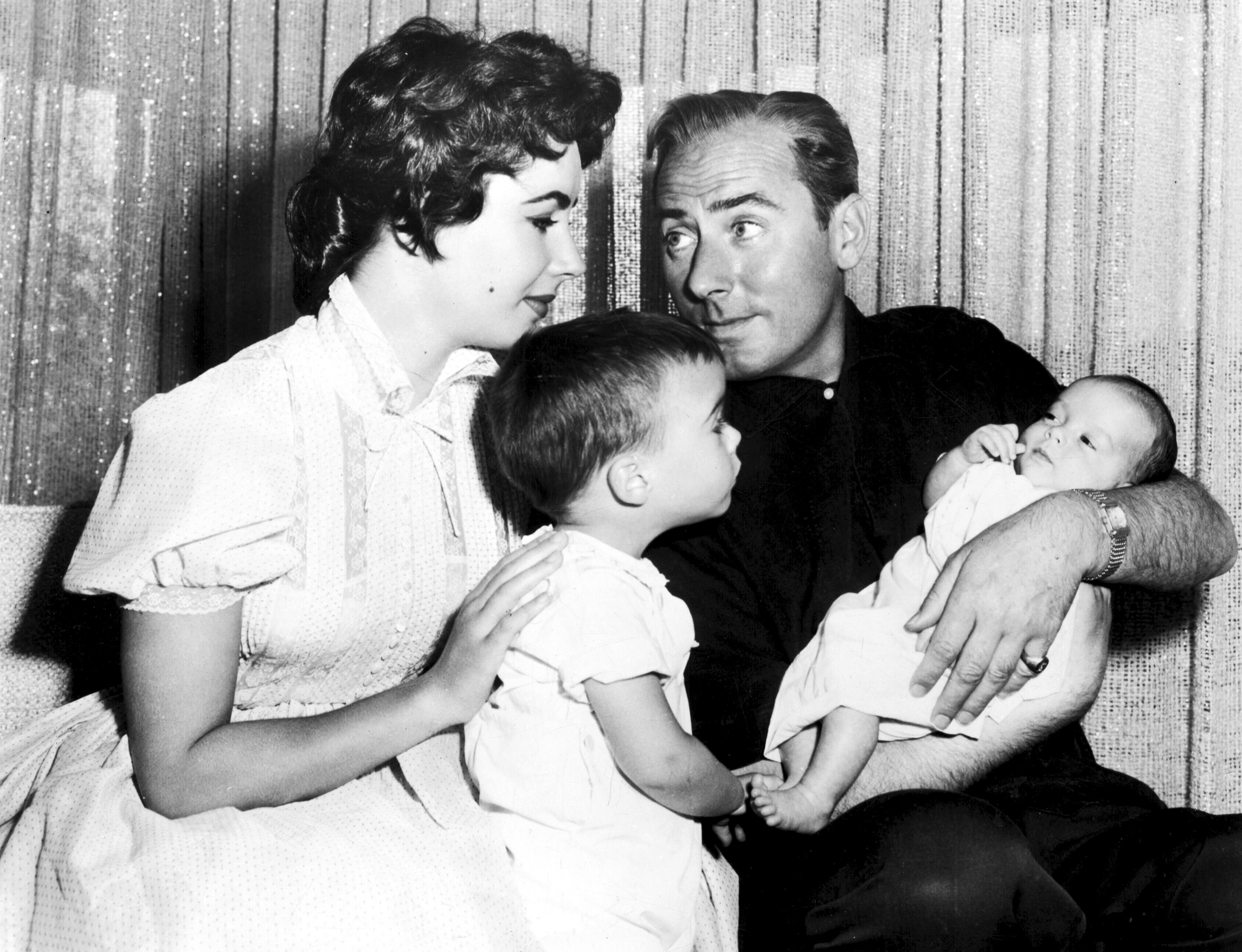 Elizabeth Taylor and Michael Wilding, who is holding their youngest son Christopher Wilding next to eldest son Michael Wilding in 1955. | Source: Getty Images