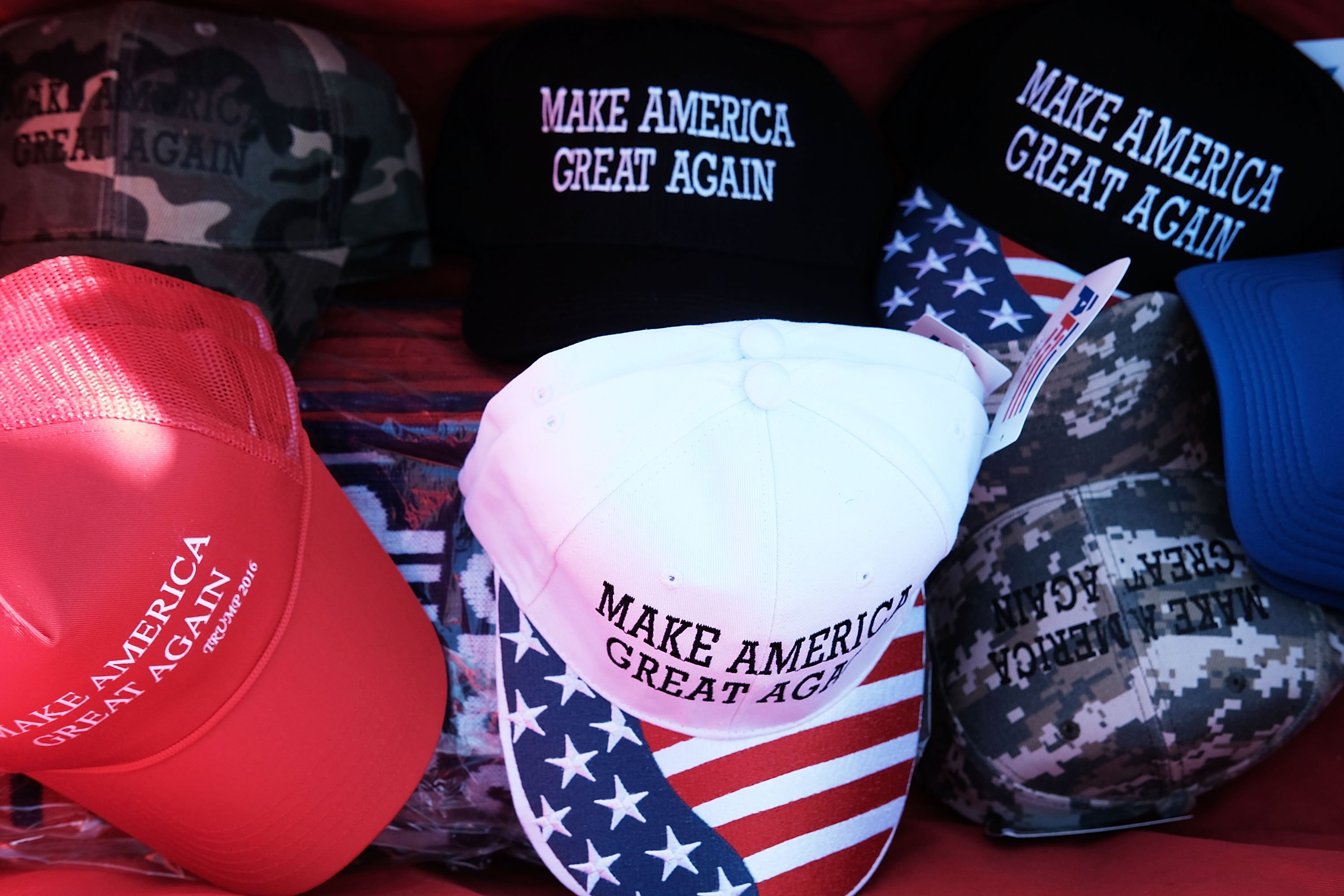 Different styles of MAGA hats being sold at a rally | Photo: Getty Images
