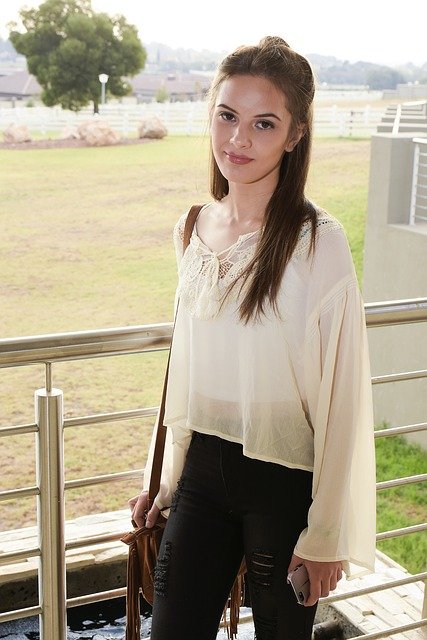 Eine junge Teenagerin mit weißer Bluse, die eine Tasche hält | Quelle: Pixabay