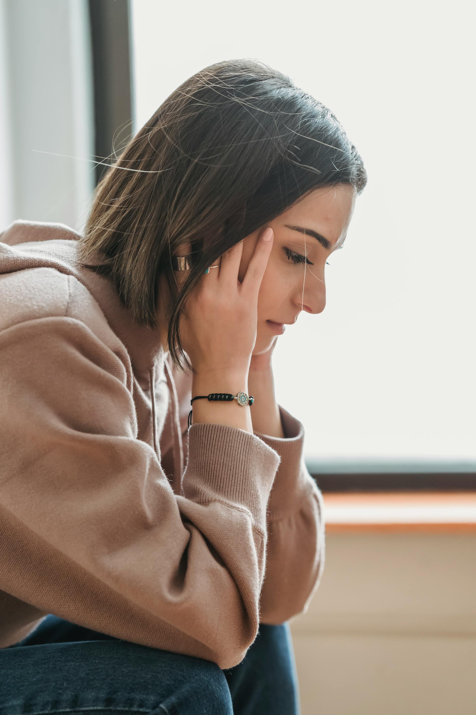 A sad woman sitting with her hands on her head | Source: Pexels