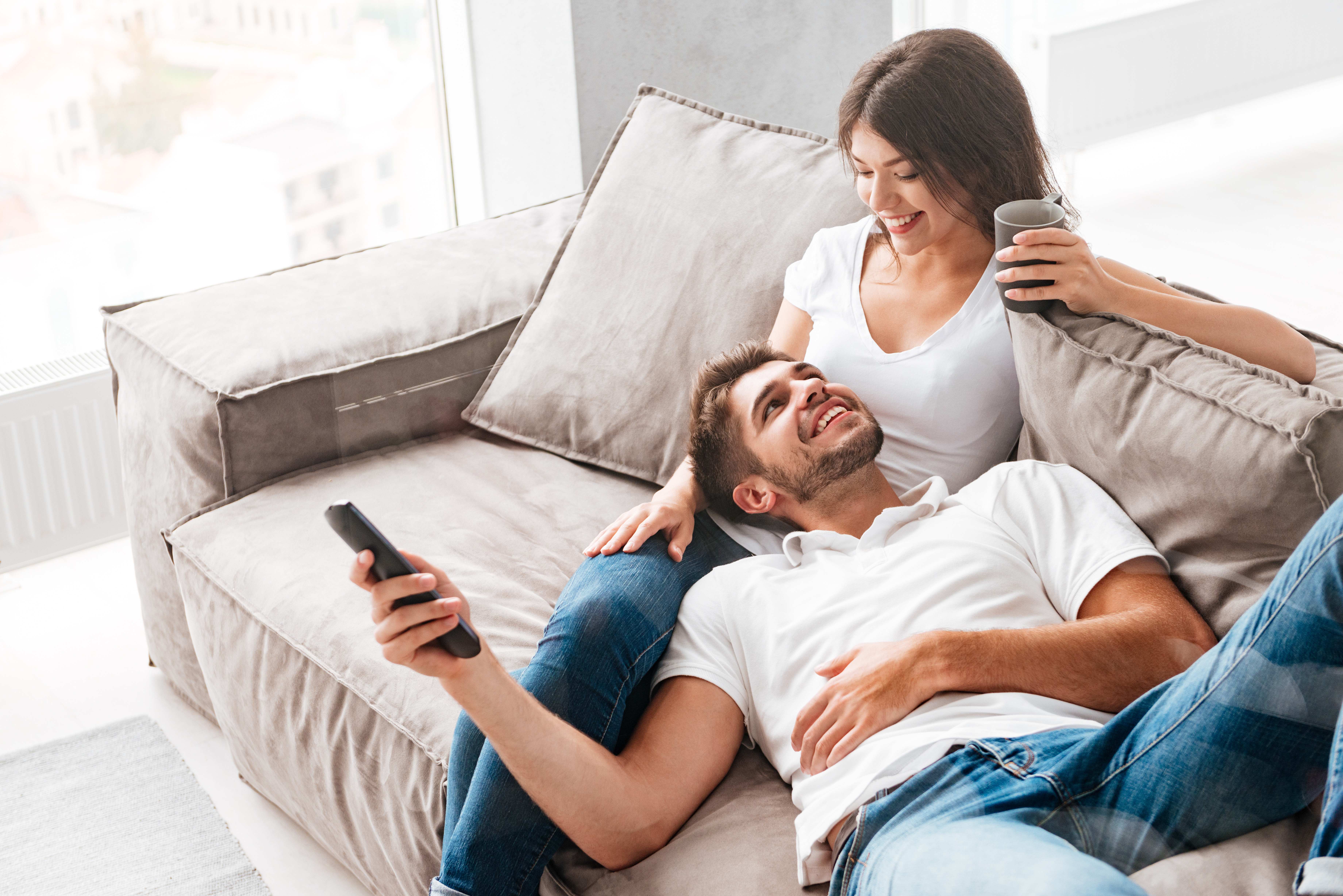A happy couple lying on a couch | Source: Shutterstock