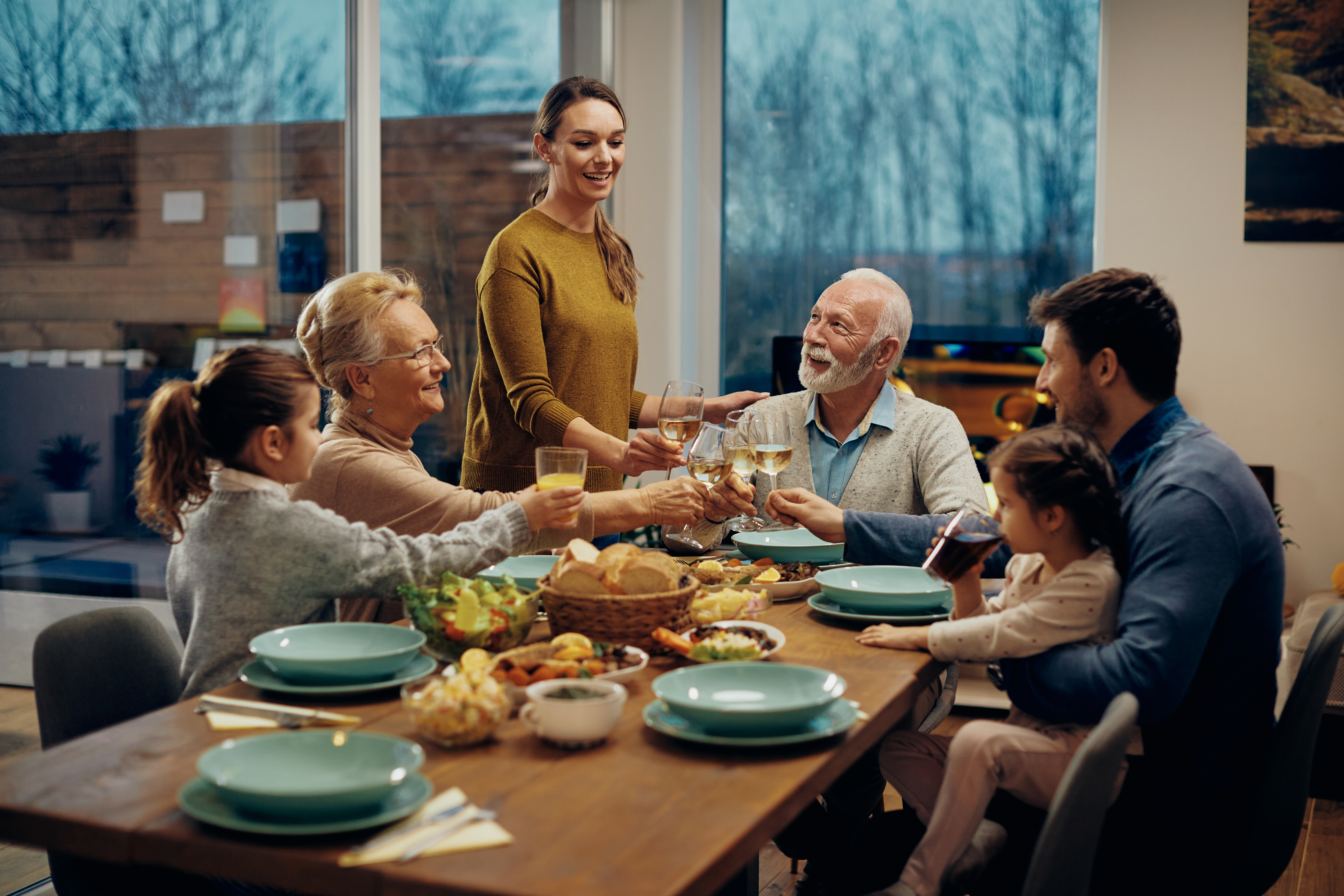 A happy extended family toasting while having lunch together in the dining room | Source: Shutterstock